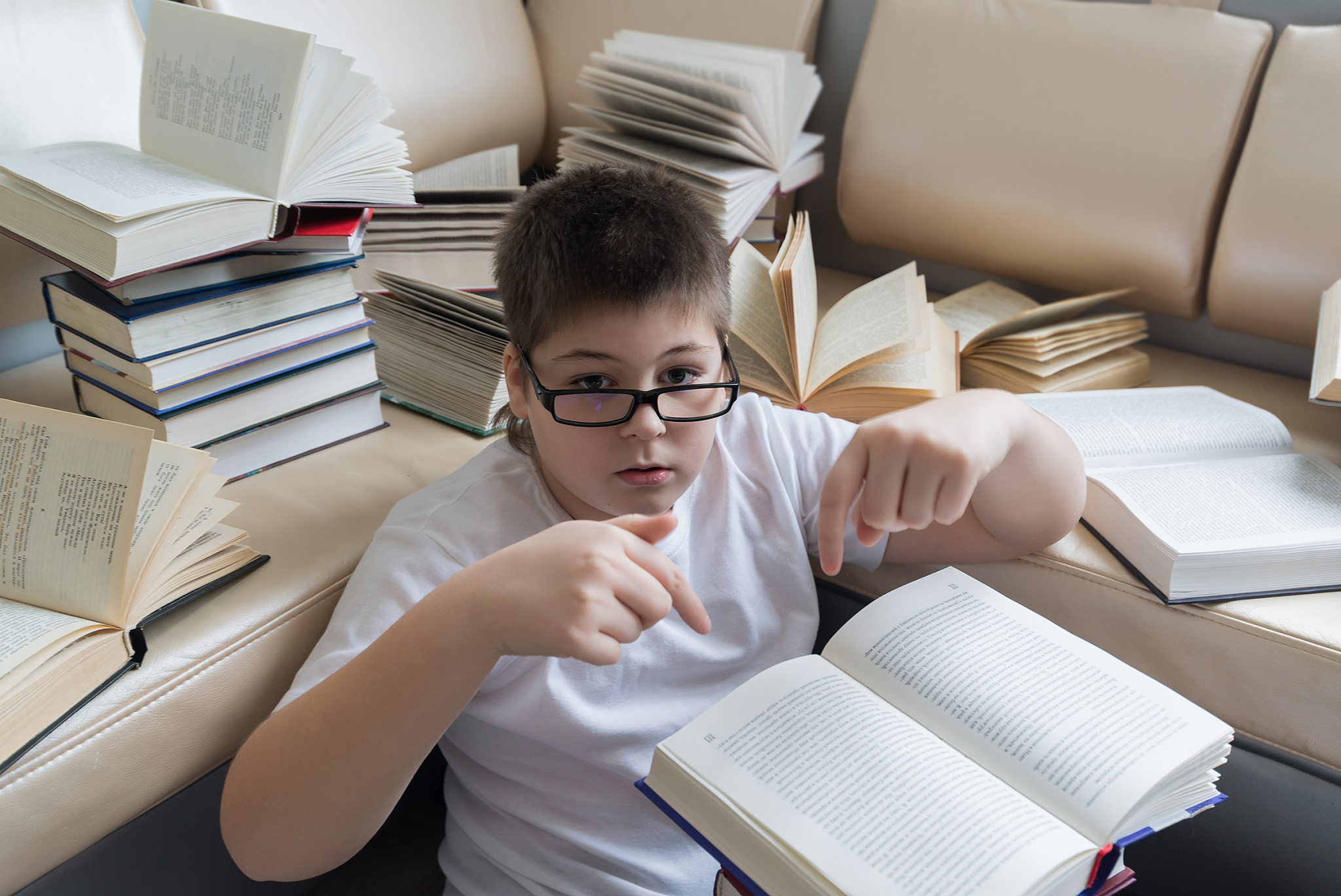 boy with glasses reading a book in  room