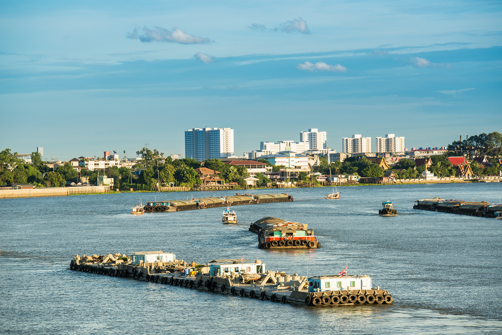 tug boat drags sand barge on chao phraya river, thailan