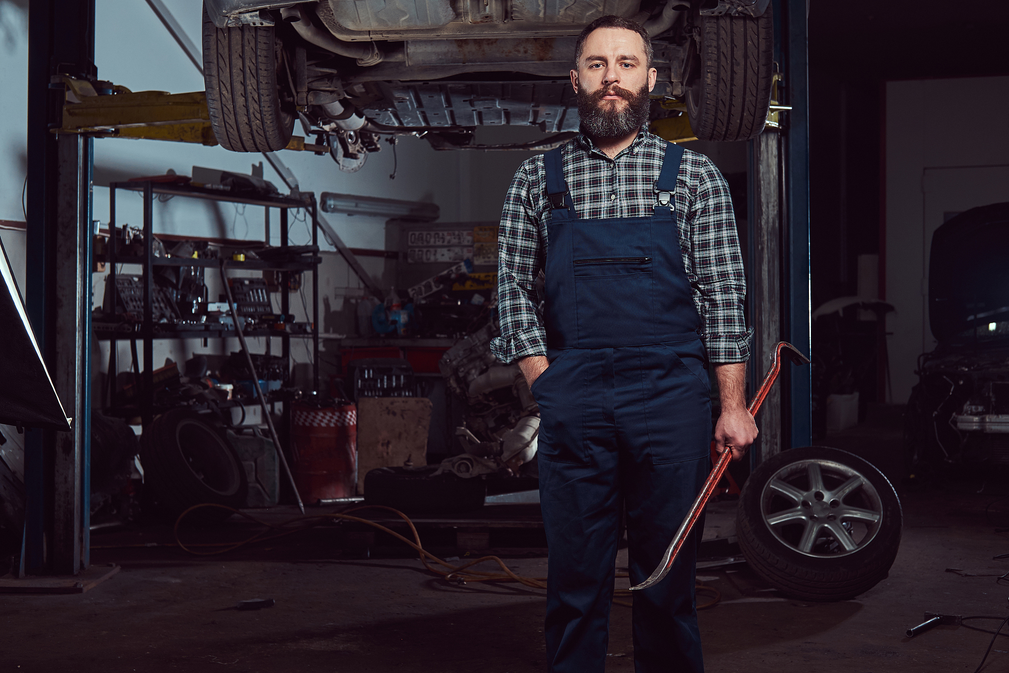 two bearded brutal mechanics repair a car on a lift in the garag