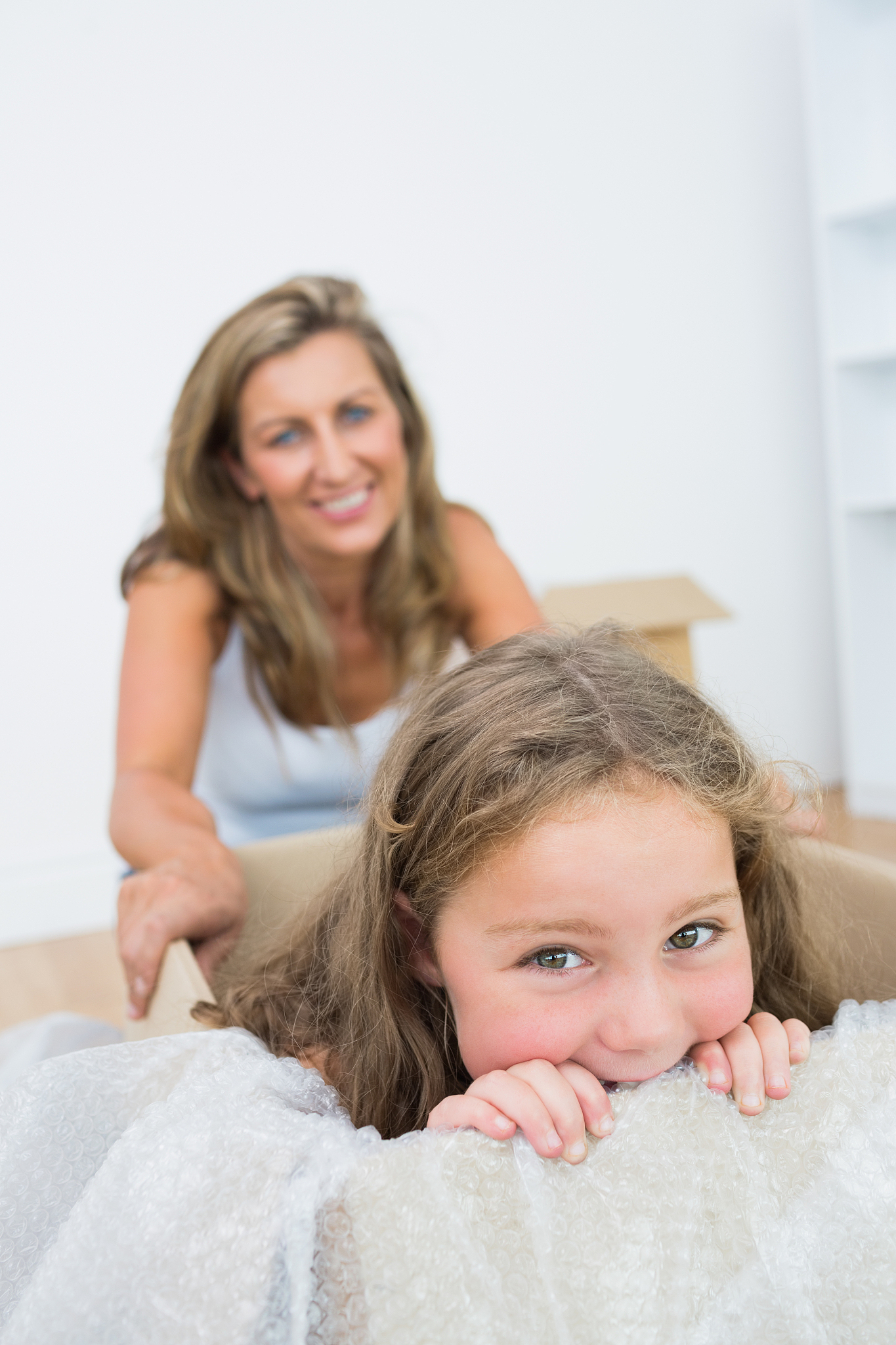 daughter sitting in the box while her mother holding her
