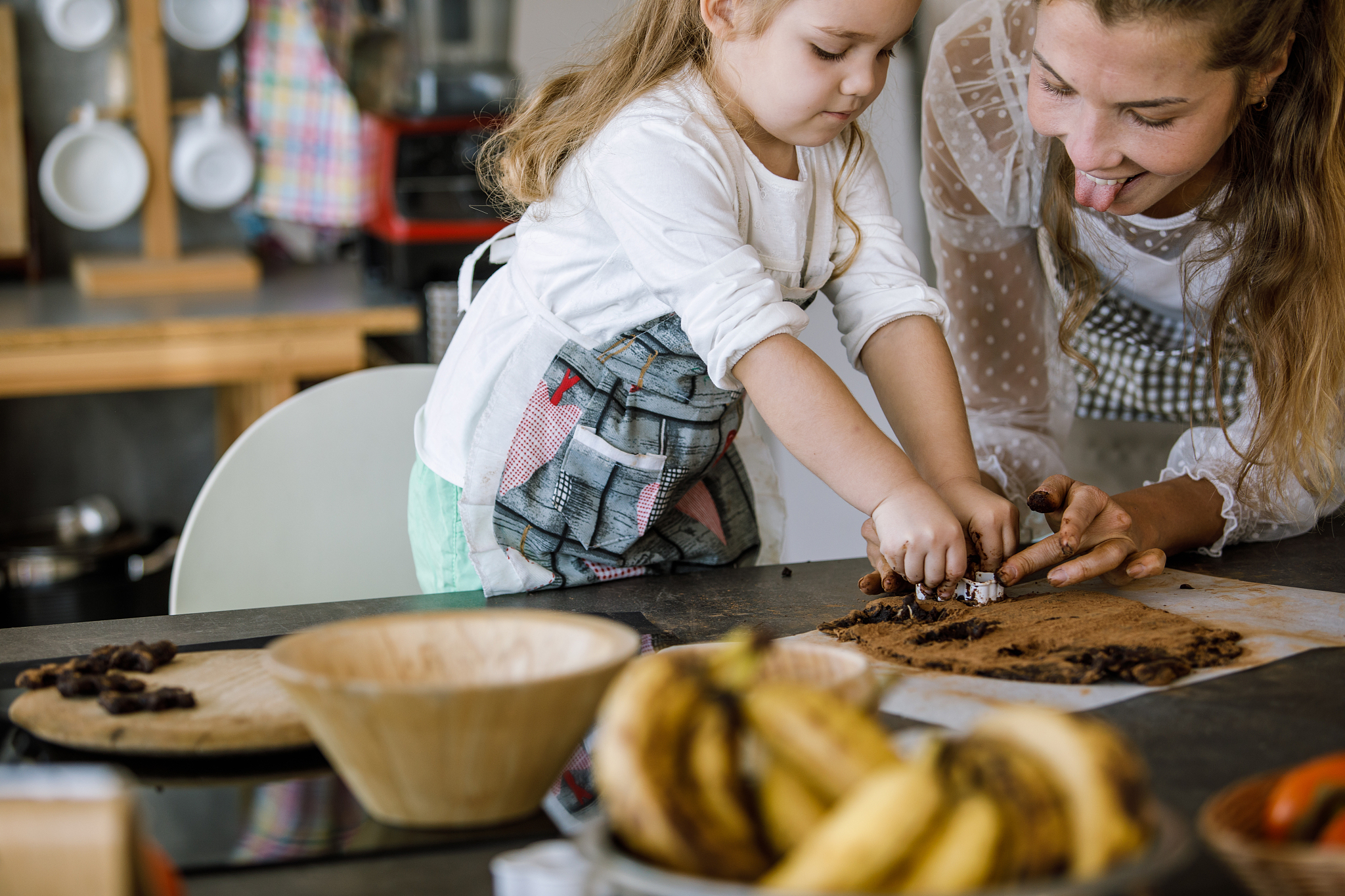 young woman having fun while cutting out cookies with her toddle