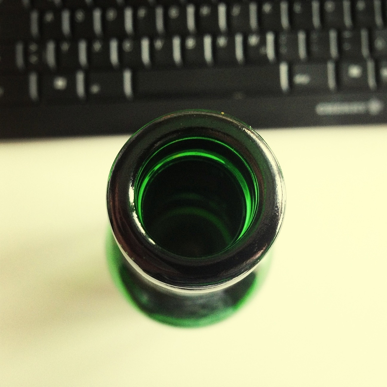 close-up of empty glass bottle against computer keyboard on tabl