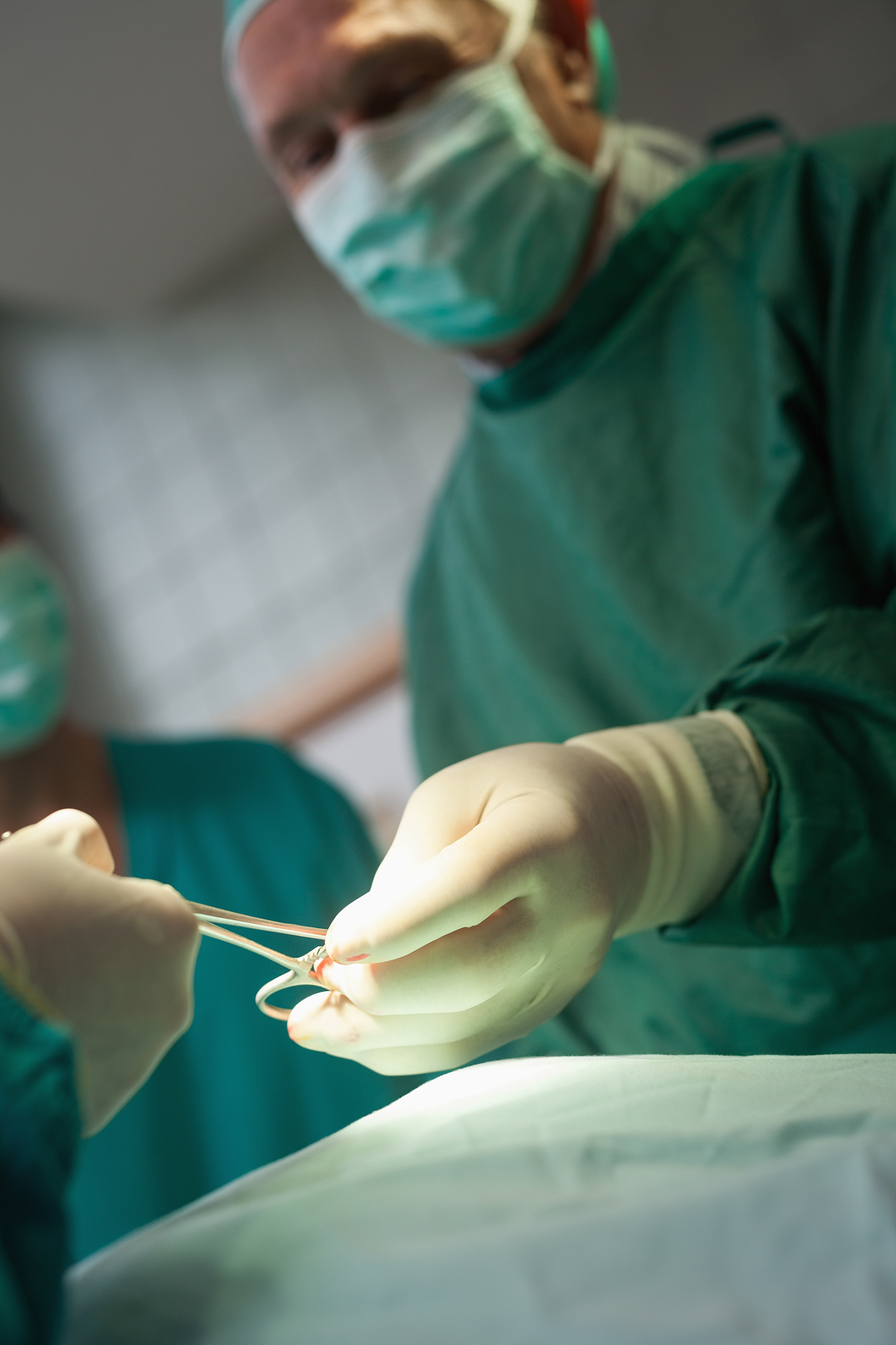 surgeon taking scissors from a gloved hand