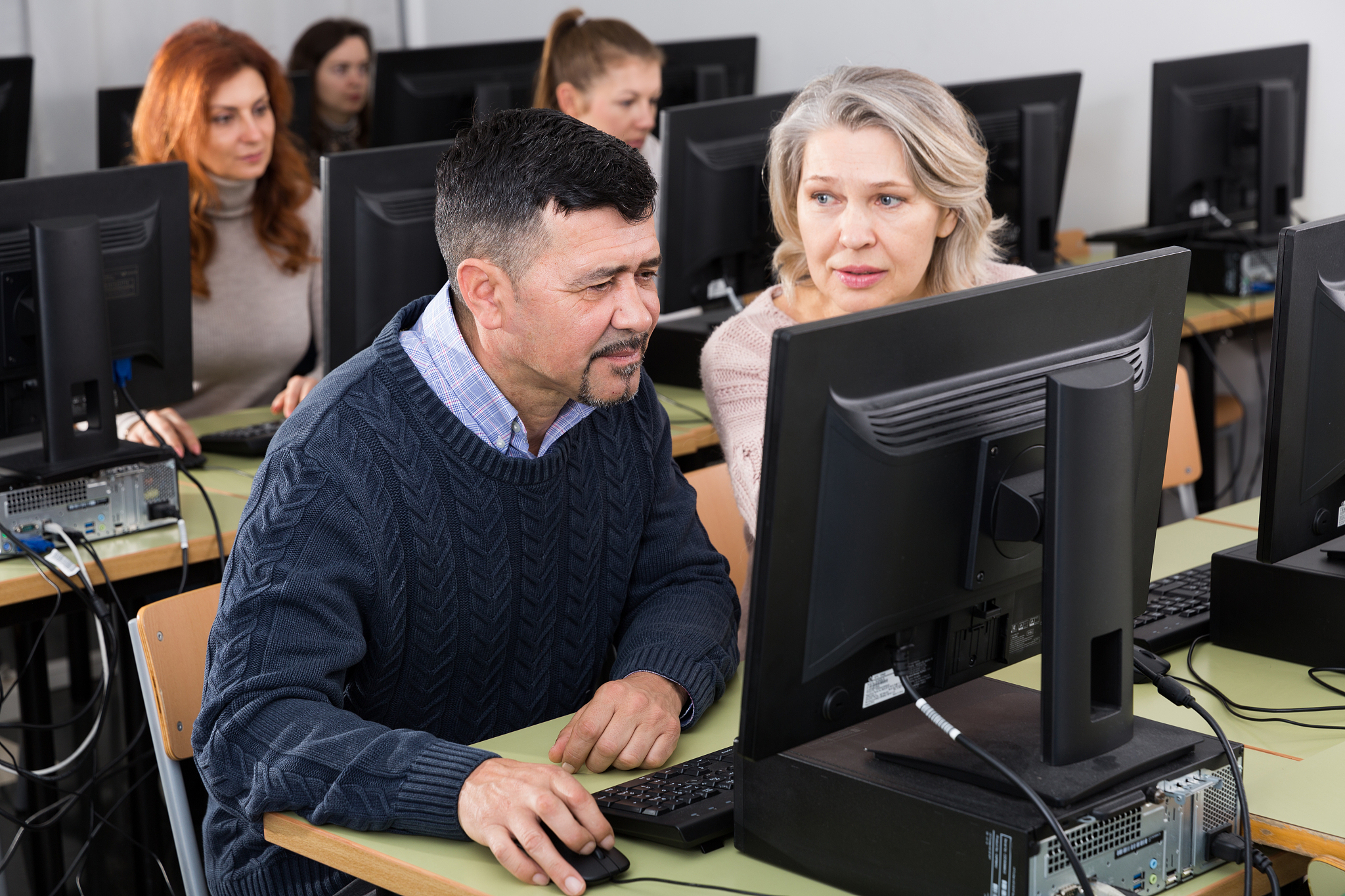 woman explaining something to man coworker, pointing at computer