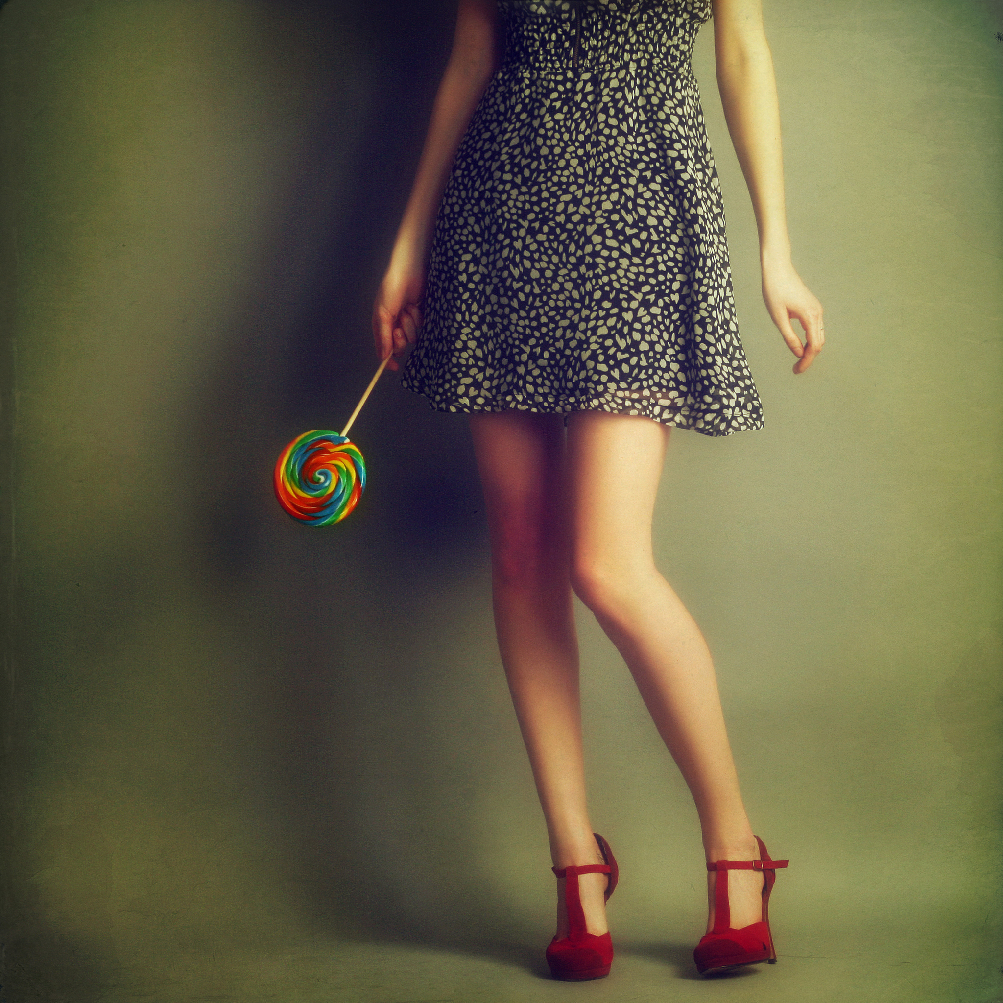 low section of woman with lollipop against wall