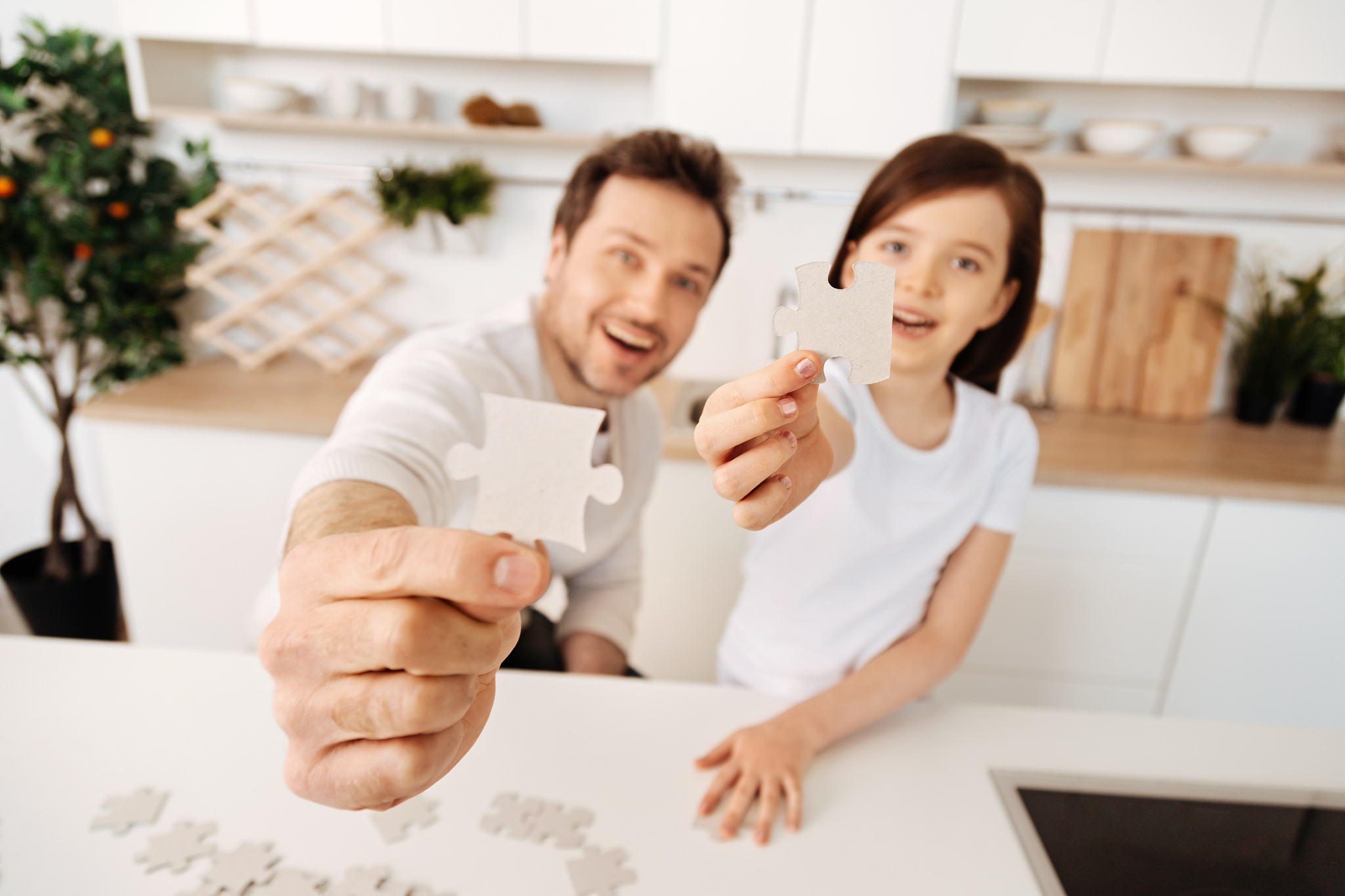 happy-looking father and daughter showing jigsaw puzzle pieces