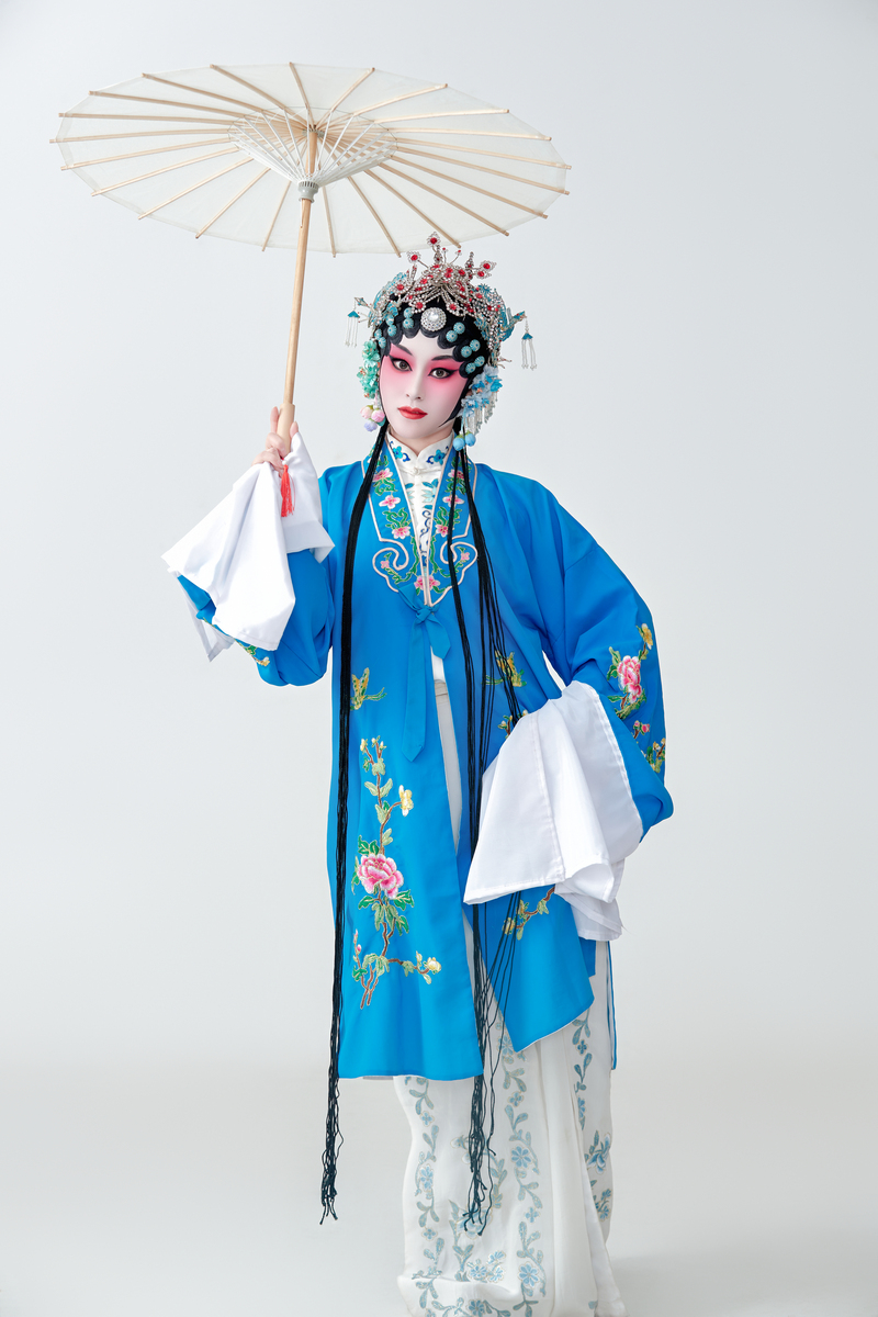 一位京剧女演员扮演青衣或花旦角色,手持油纸伞.