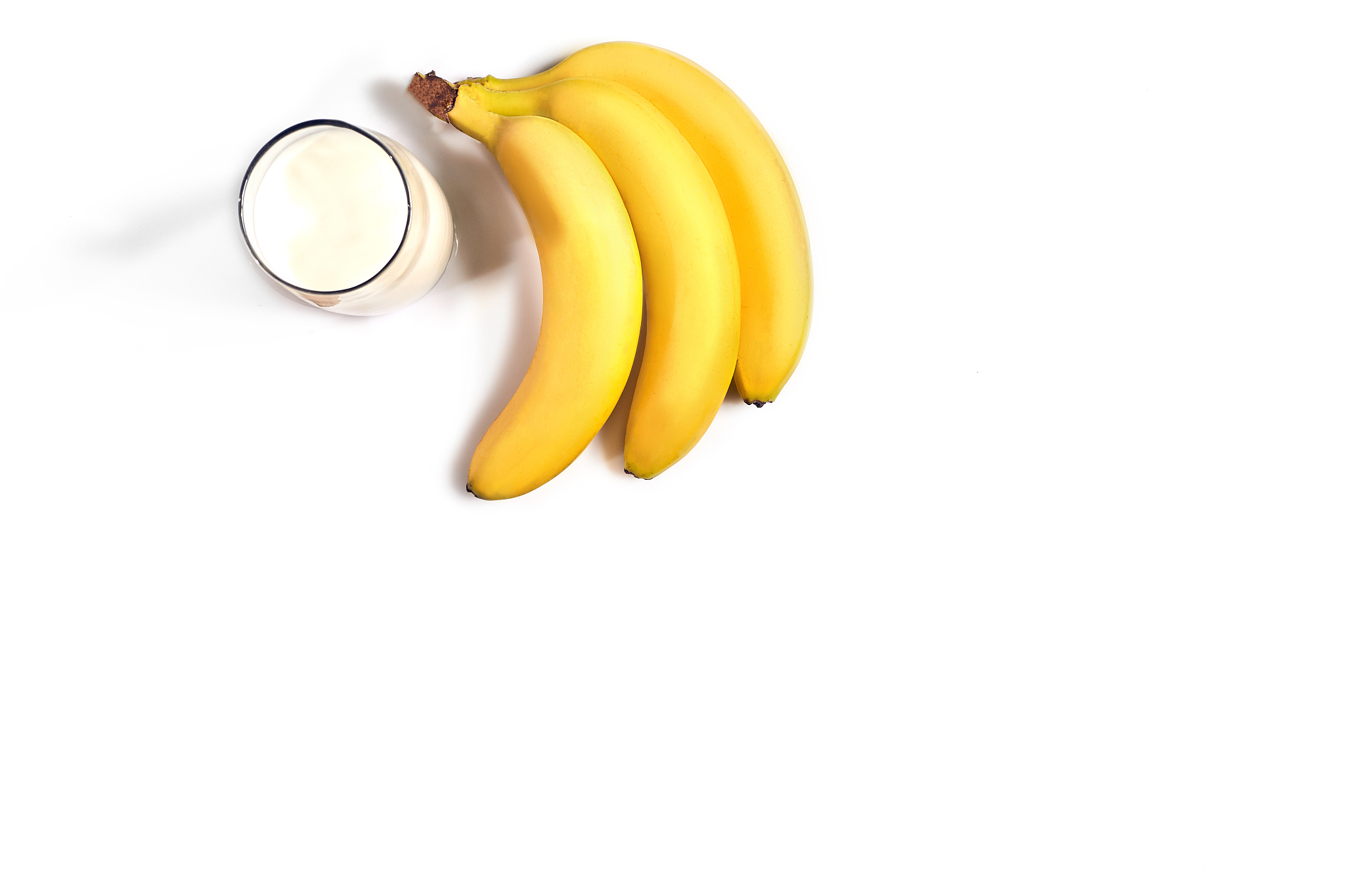 glass of milk with bananas over white background. top view