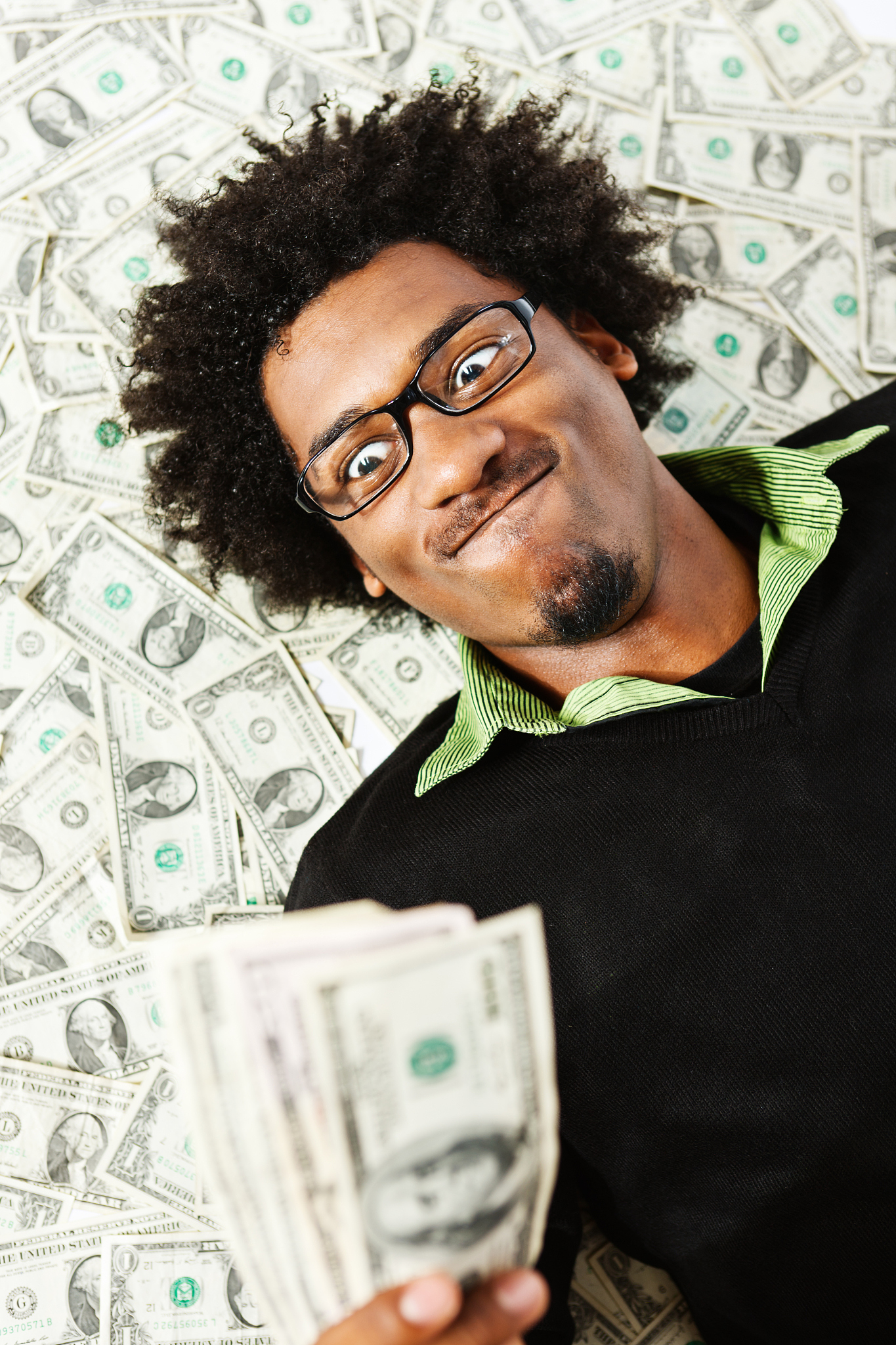 all mine! young man with multiple dollars is triumphant