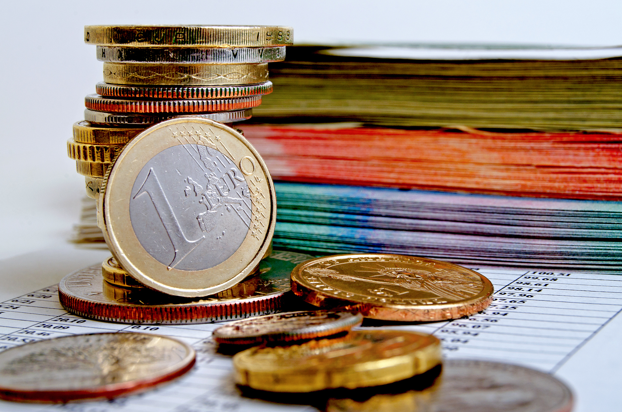 euro coin and a bundle of money on the financial report.