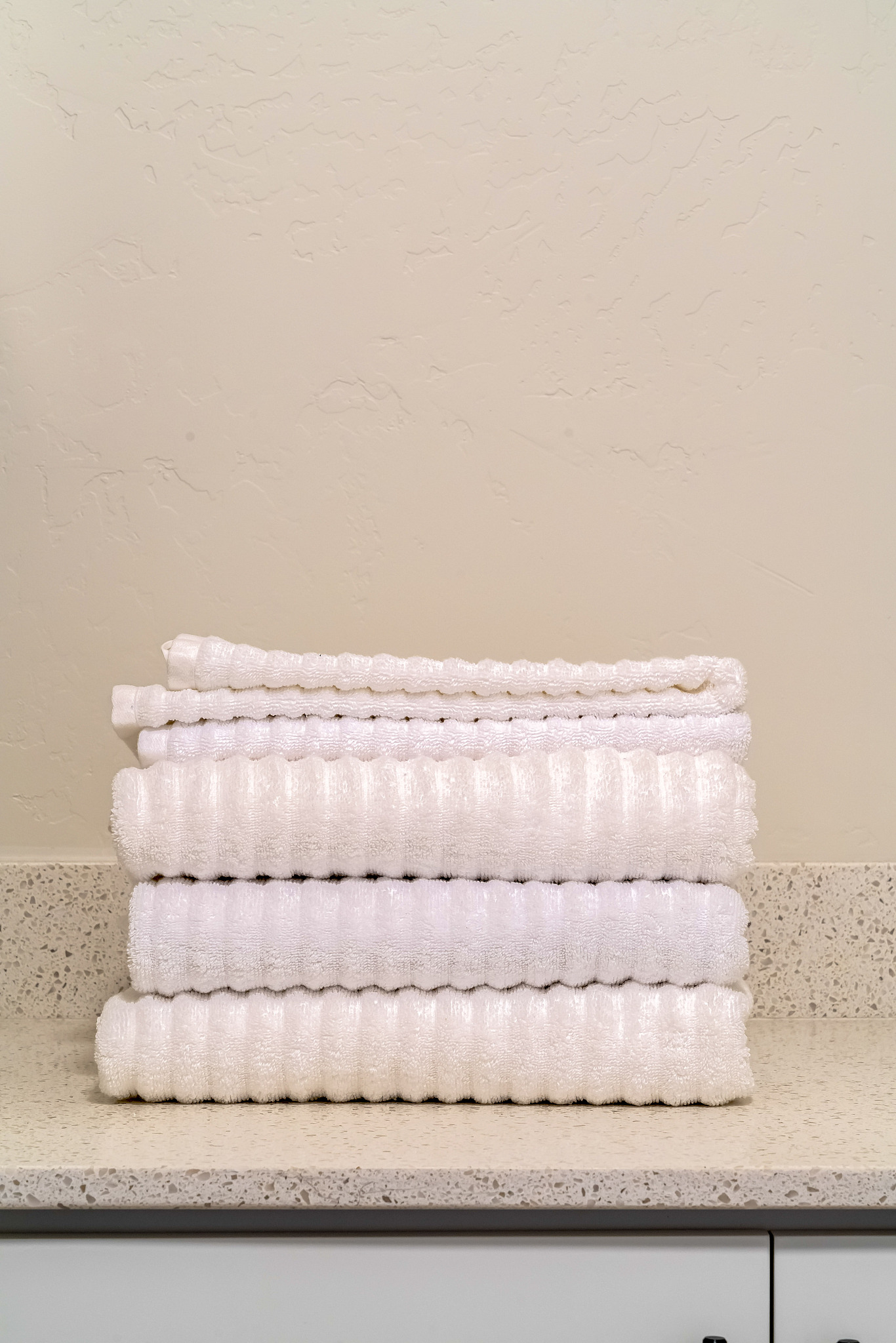 stack of clean white ribbed towels in a bathroom