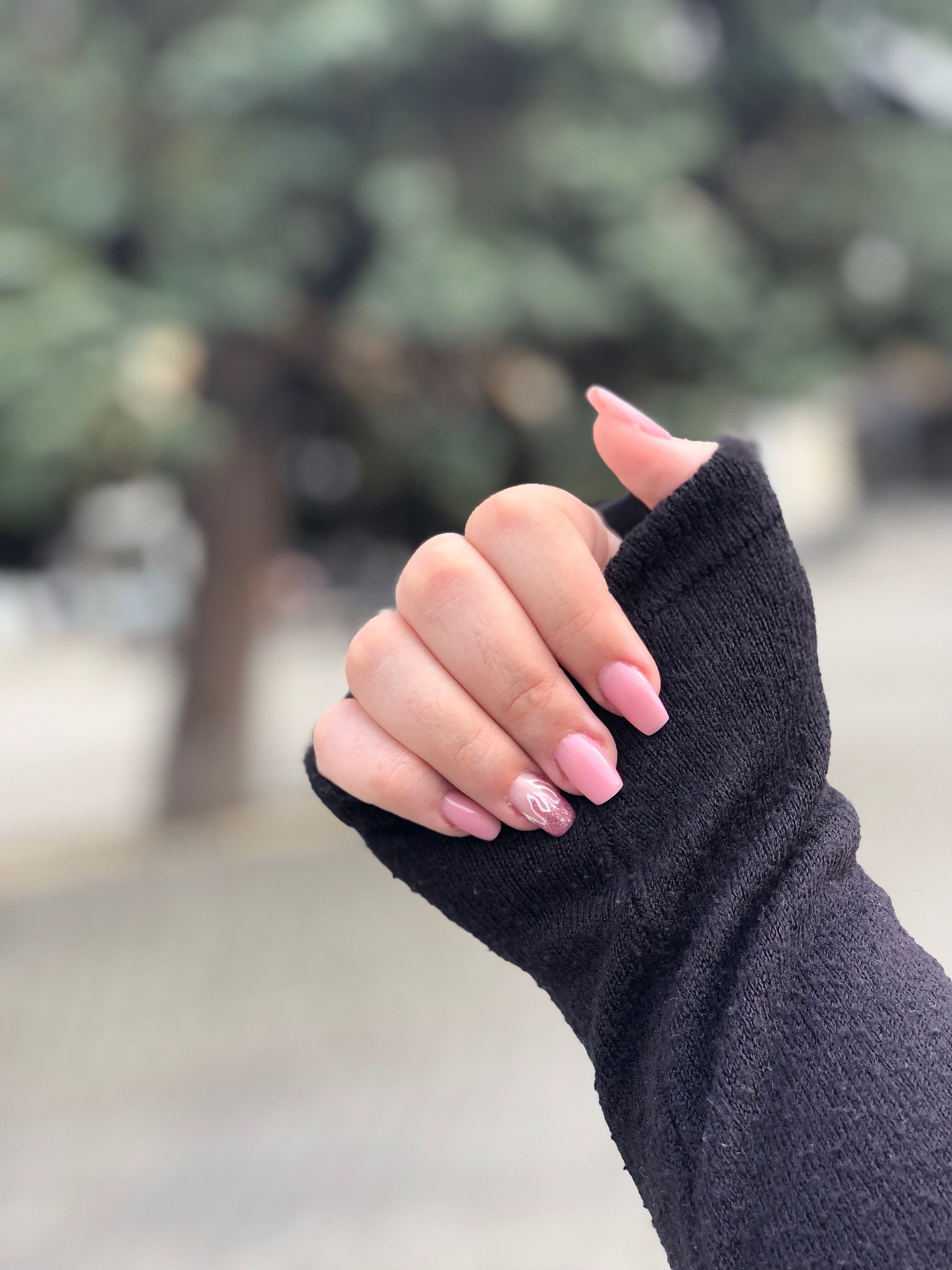 cropped hand of woman with painted fingernails against trees