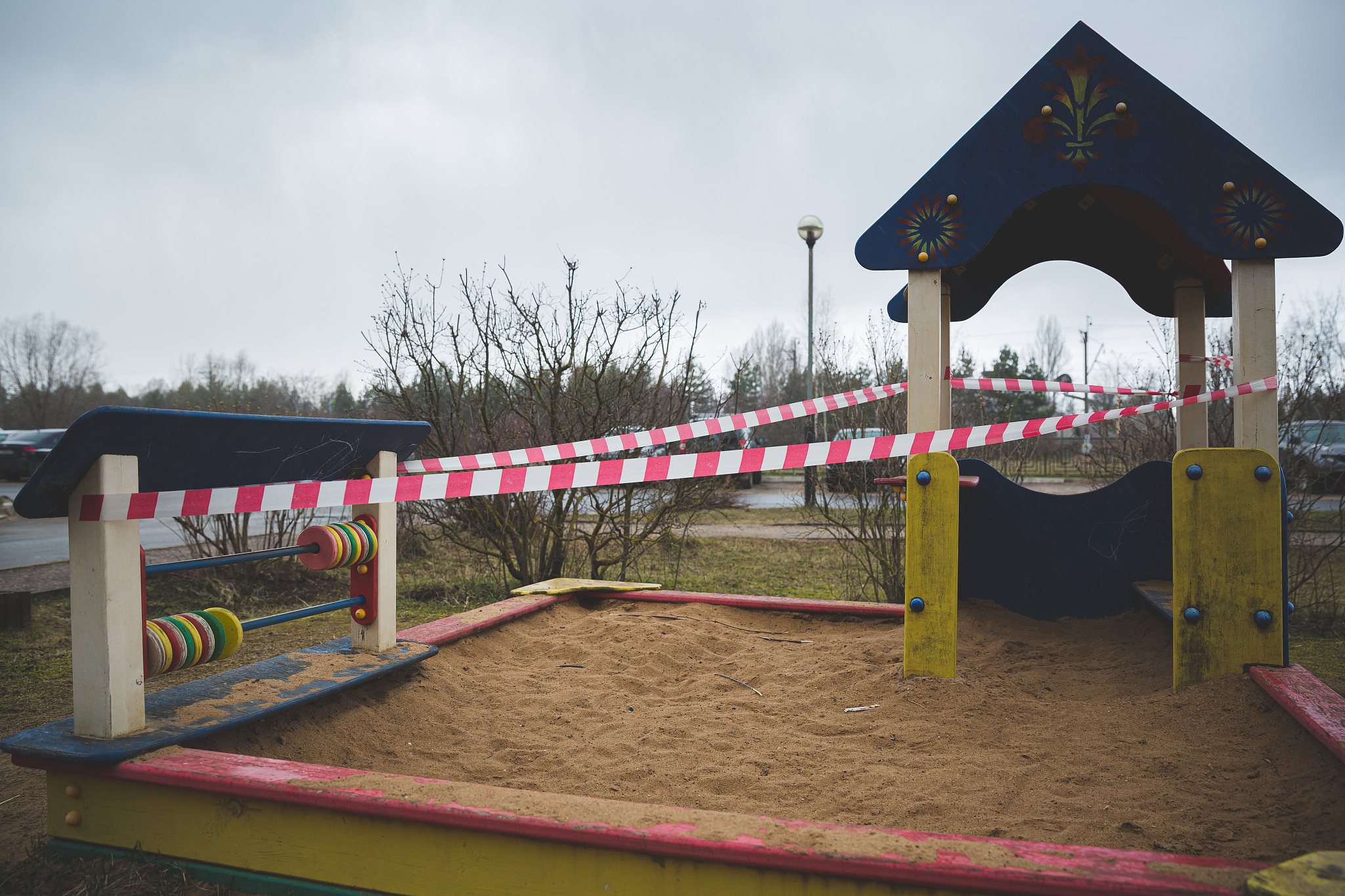 a children's sandbox next to the house is fenced with warning ta