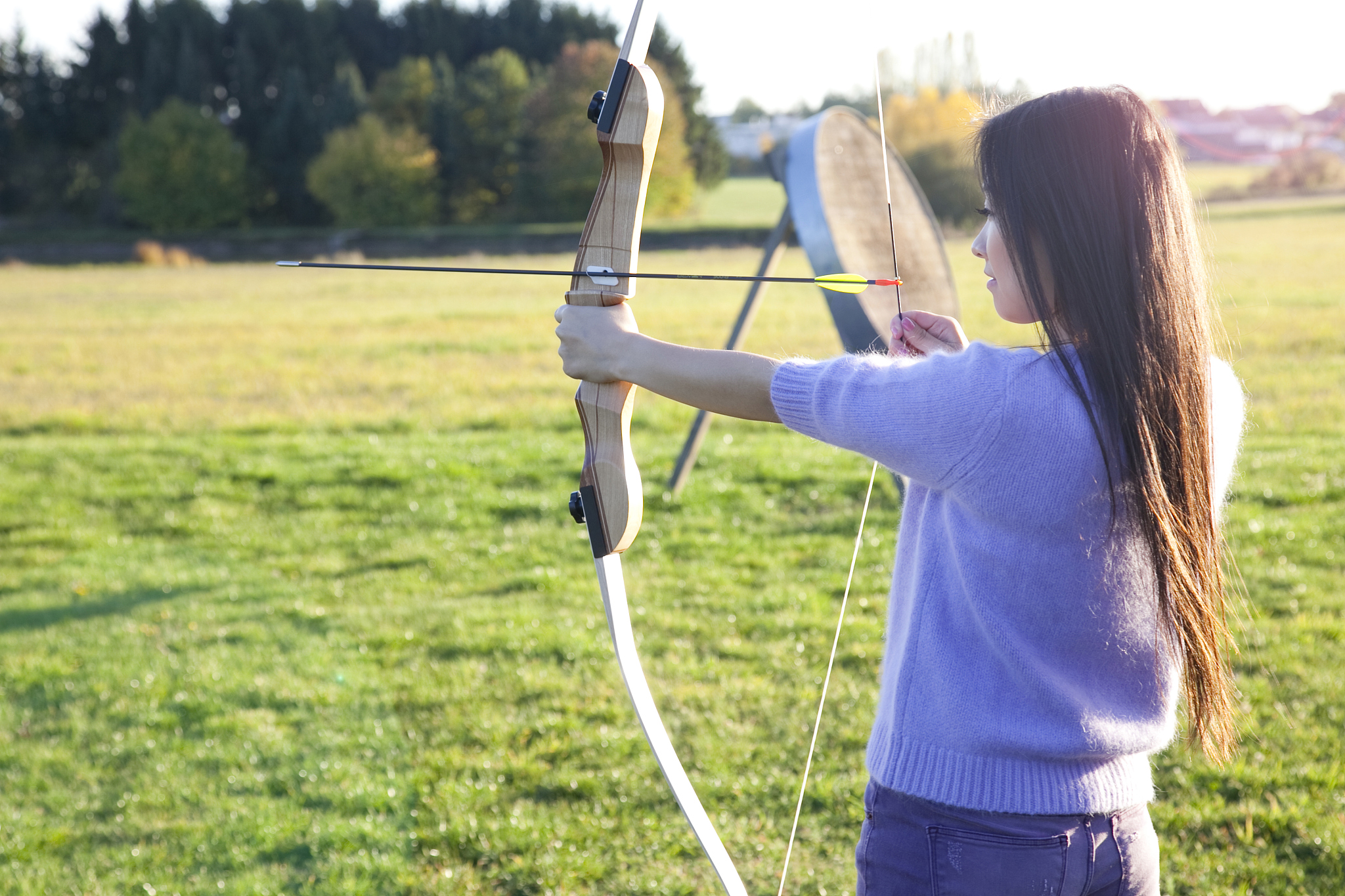 a woman practising archery in the countryside