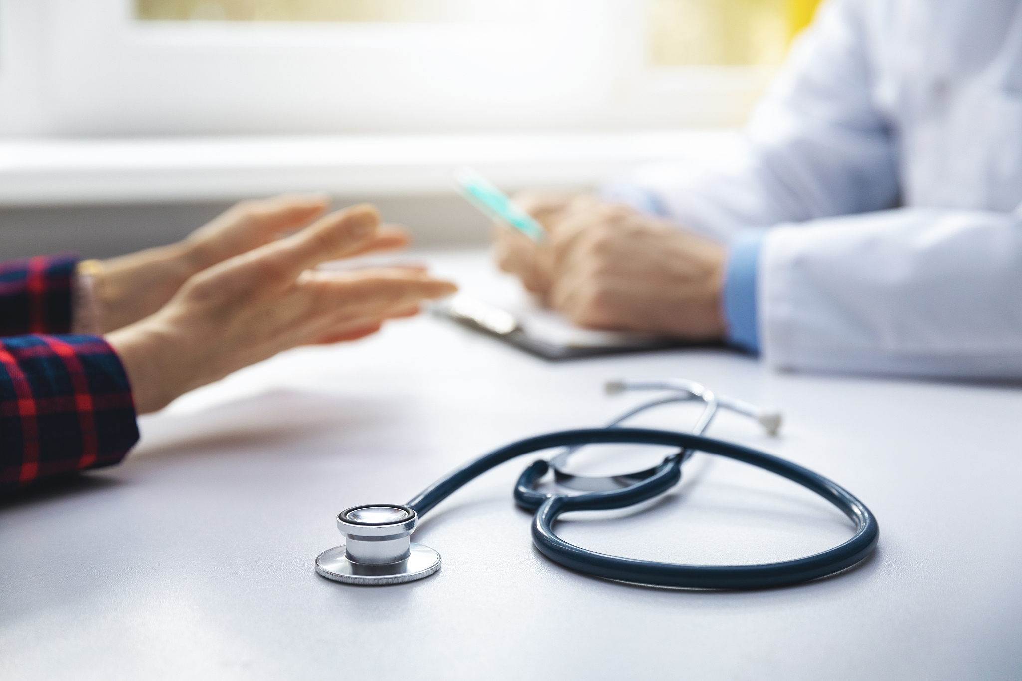 medical consultation - doctor talking to patient in clinic offic