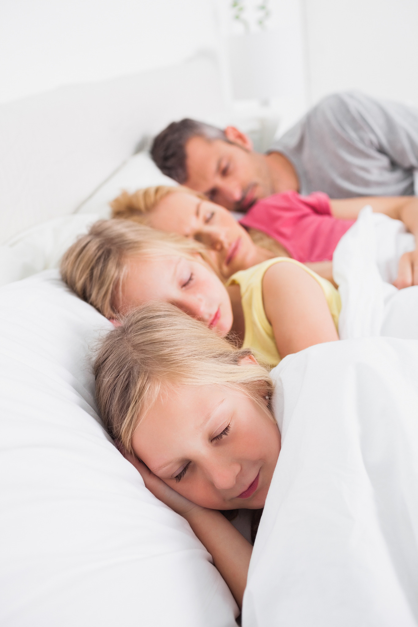 parents sleeping with their cute twins in bed