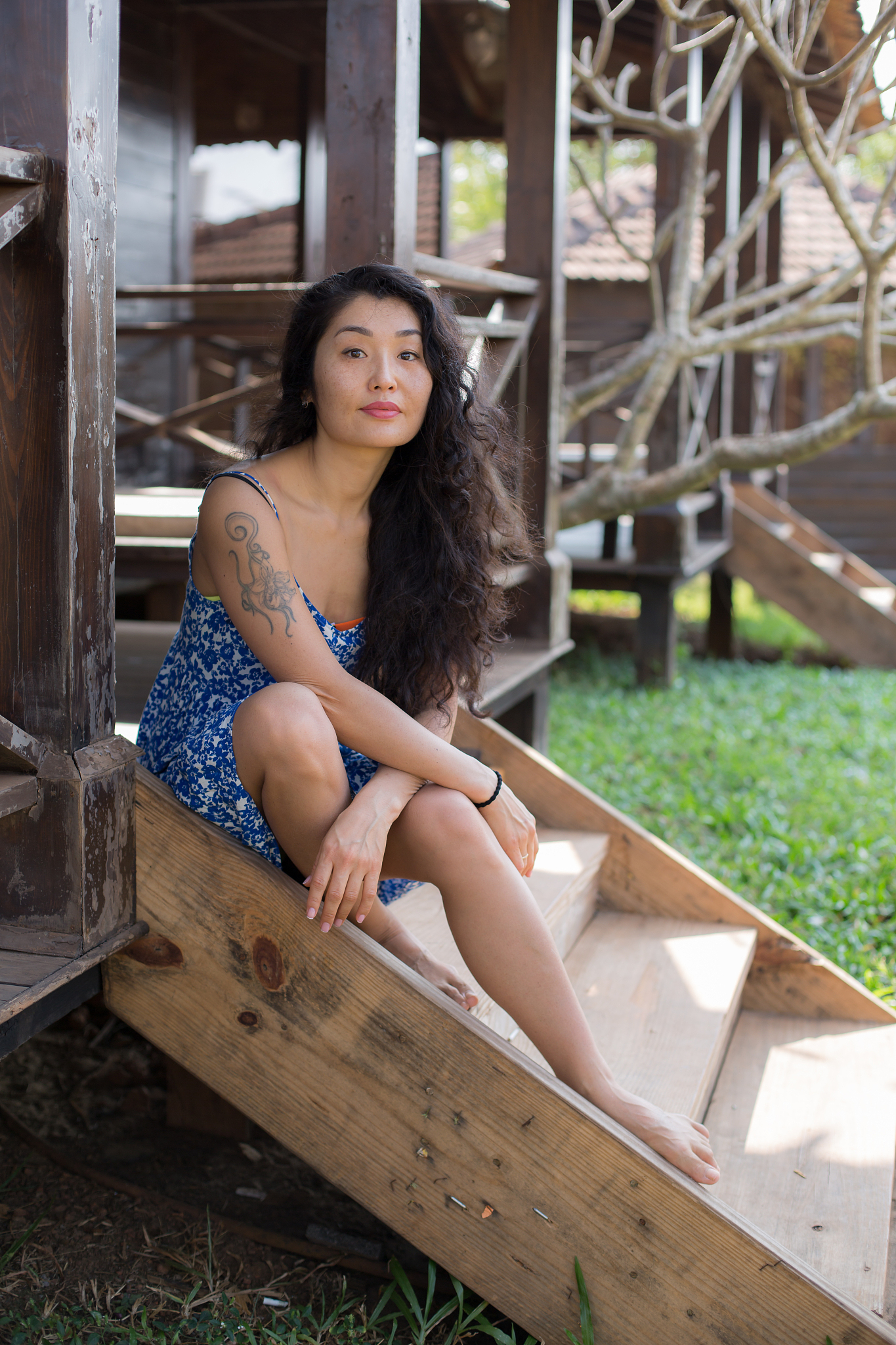 beautiful girl in a blue dress sits on the steps of a bungalow