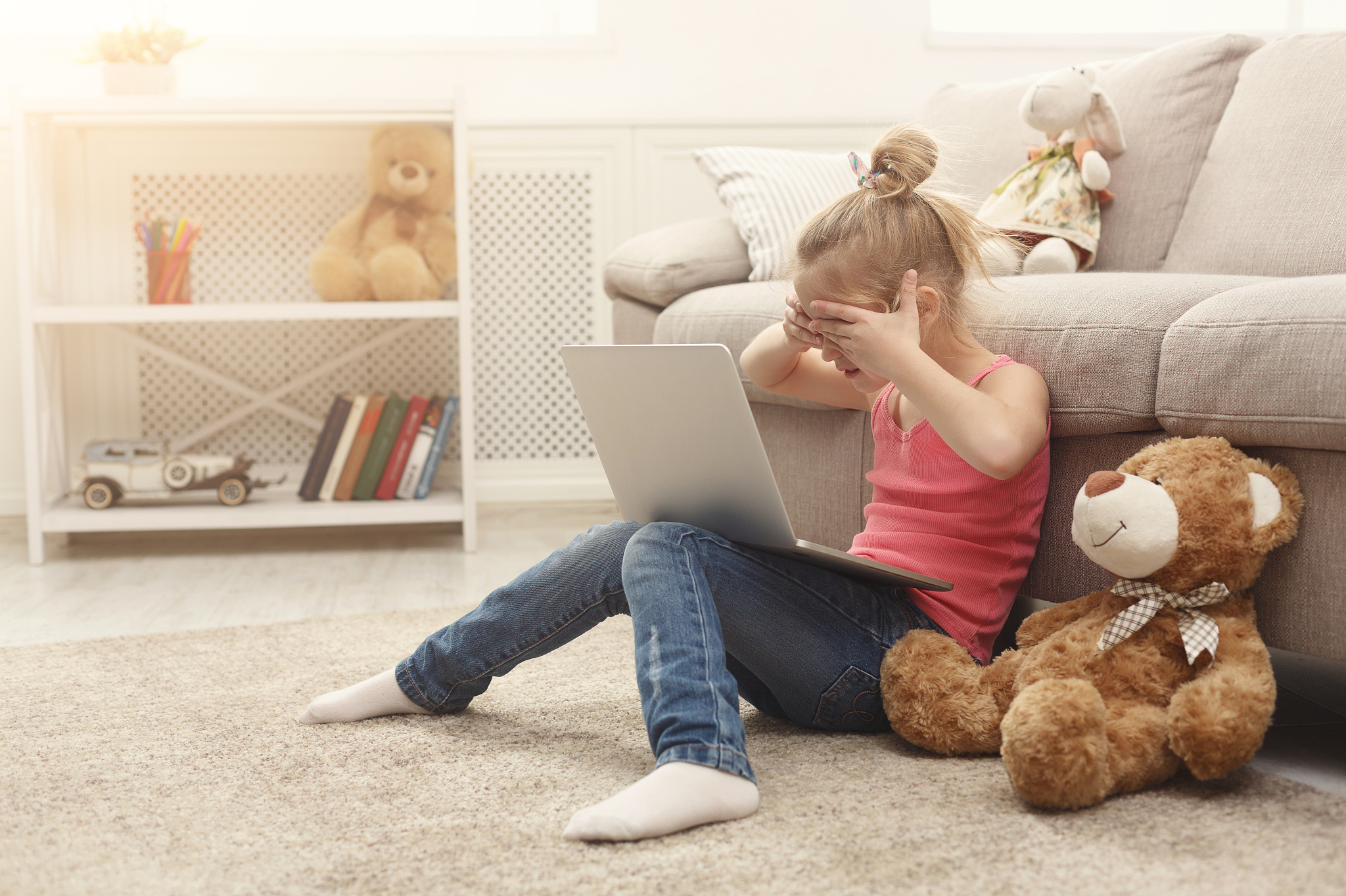 scared casual little girl watching movie on laptop while sitting