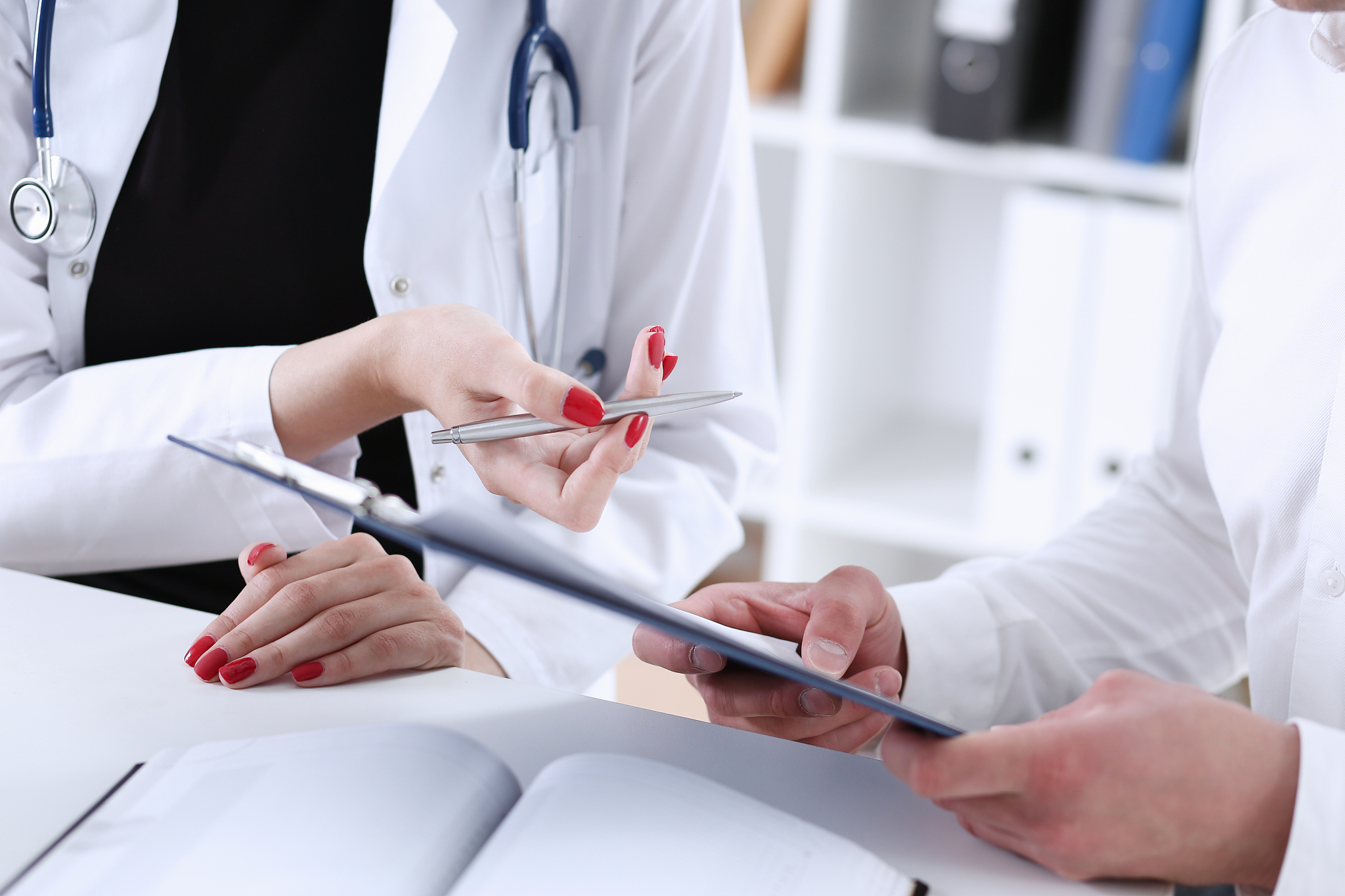 female doctor hand hold silver pen and showing pad