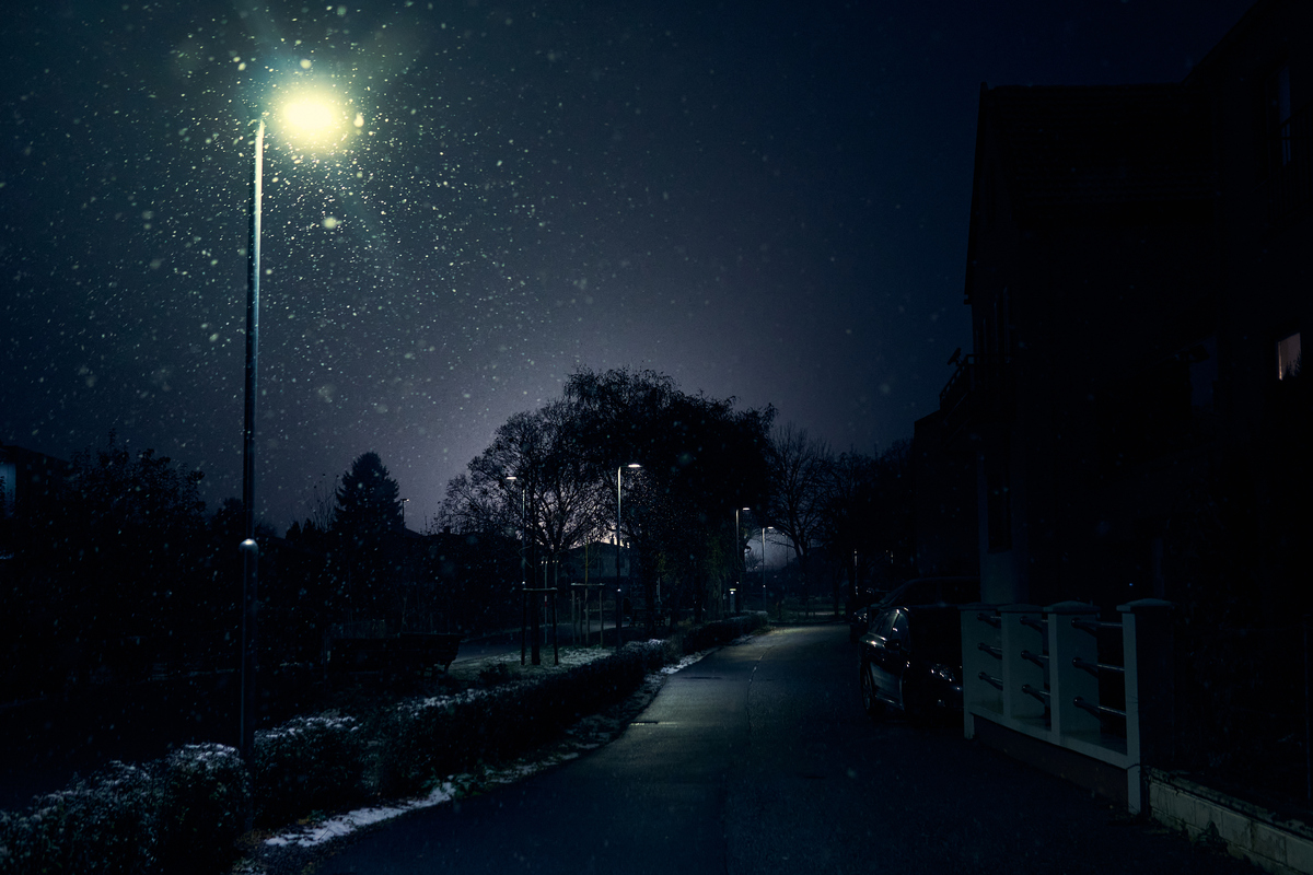 夜间城市安静的街道,灯光洒在飘落的雪上