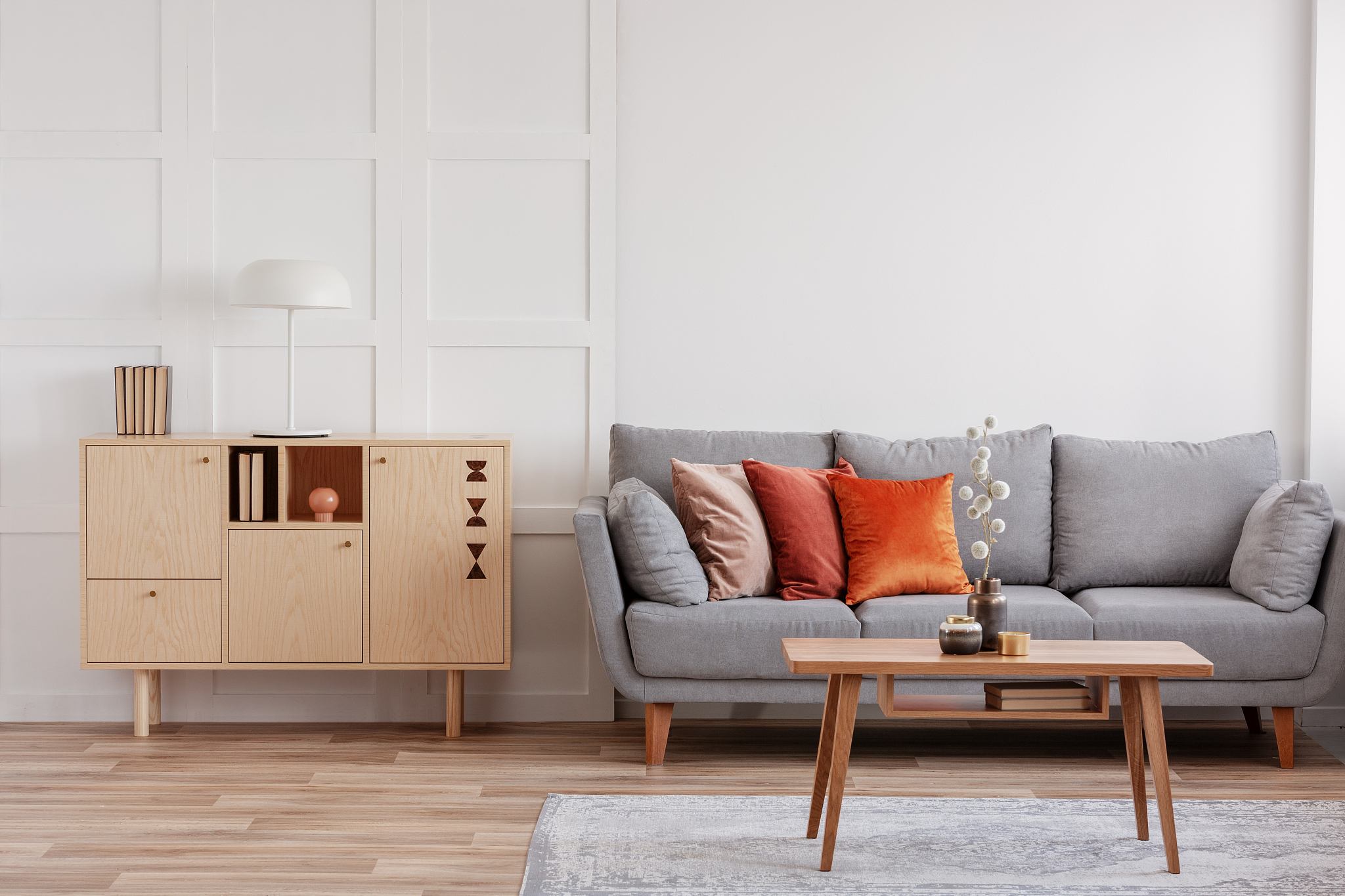 vintage wooden commode next to grey scandinavian sofa with pillo