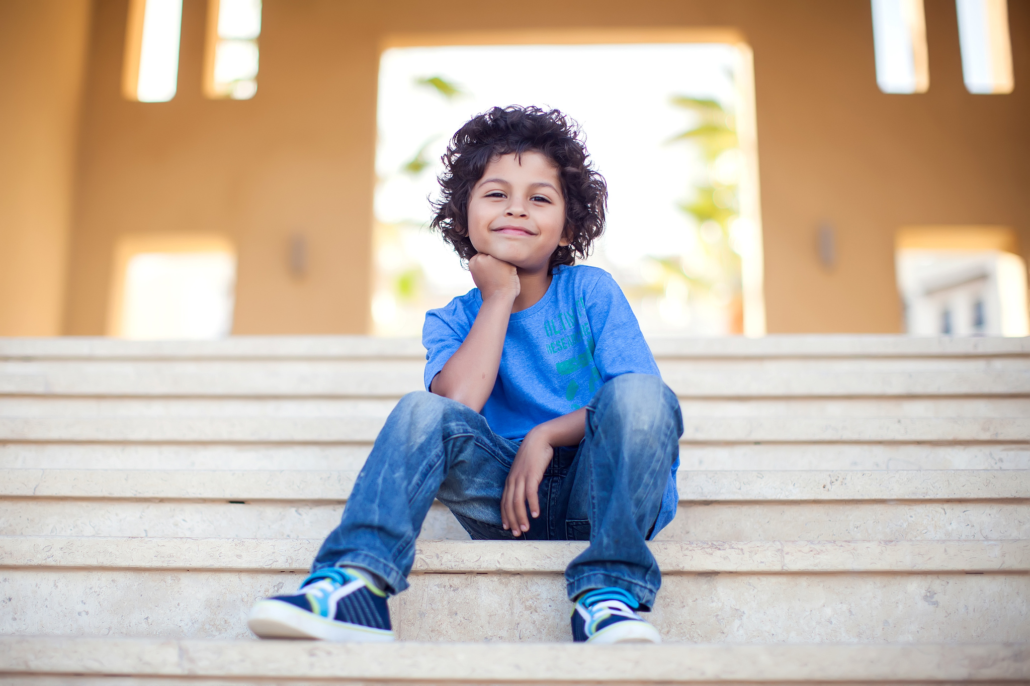 a portrait of smiling kid boy sitting on stages outdoor. childre