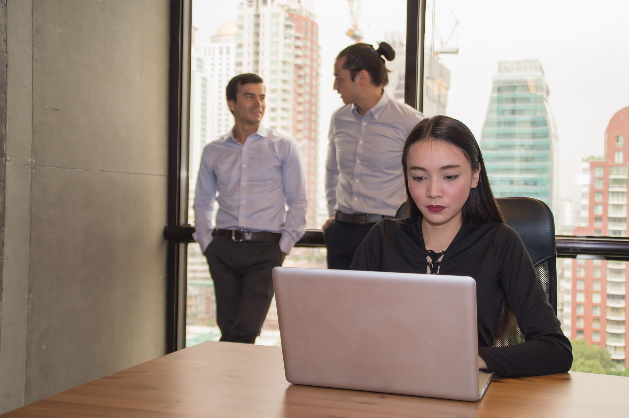 businesswoman using laptop on desk while coworkers discussing in