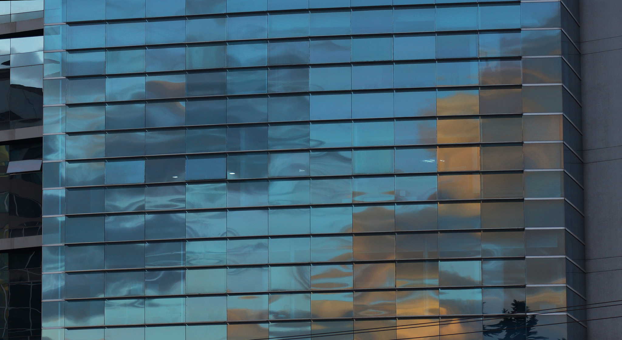 approach to the glass windows reflecting a blue sky of a modern 