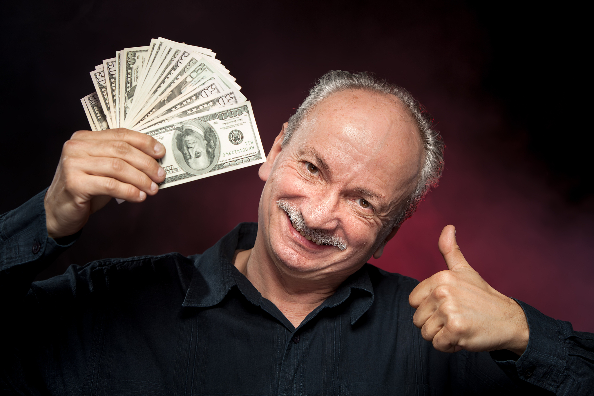 elderly man showing fan of money