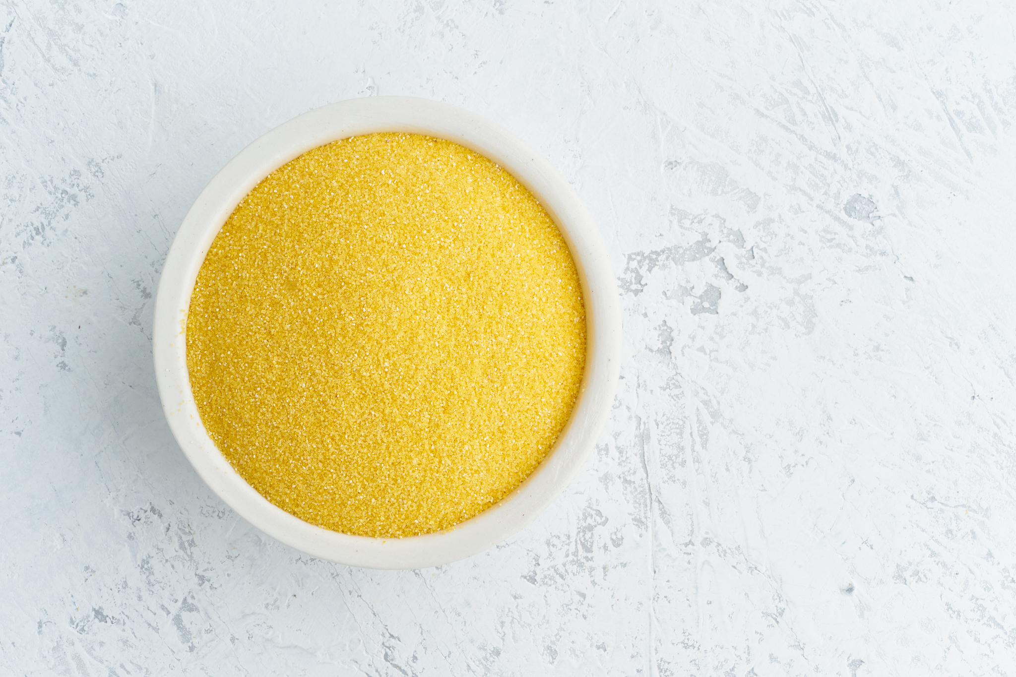 corn, polenta in white bowl on white background. dried cereals i