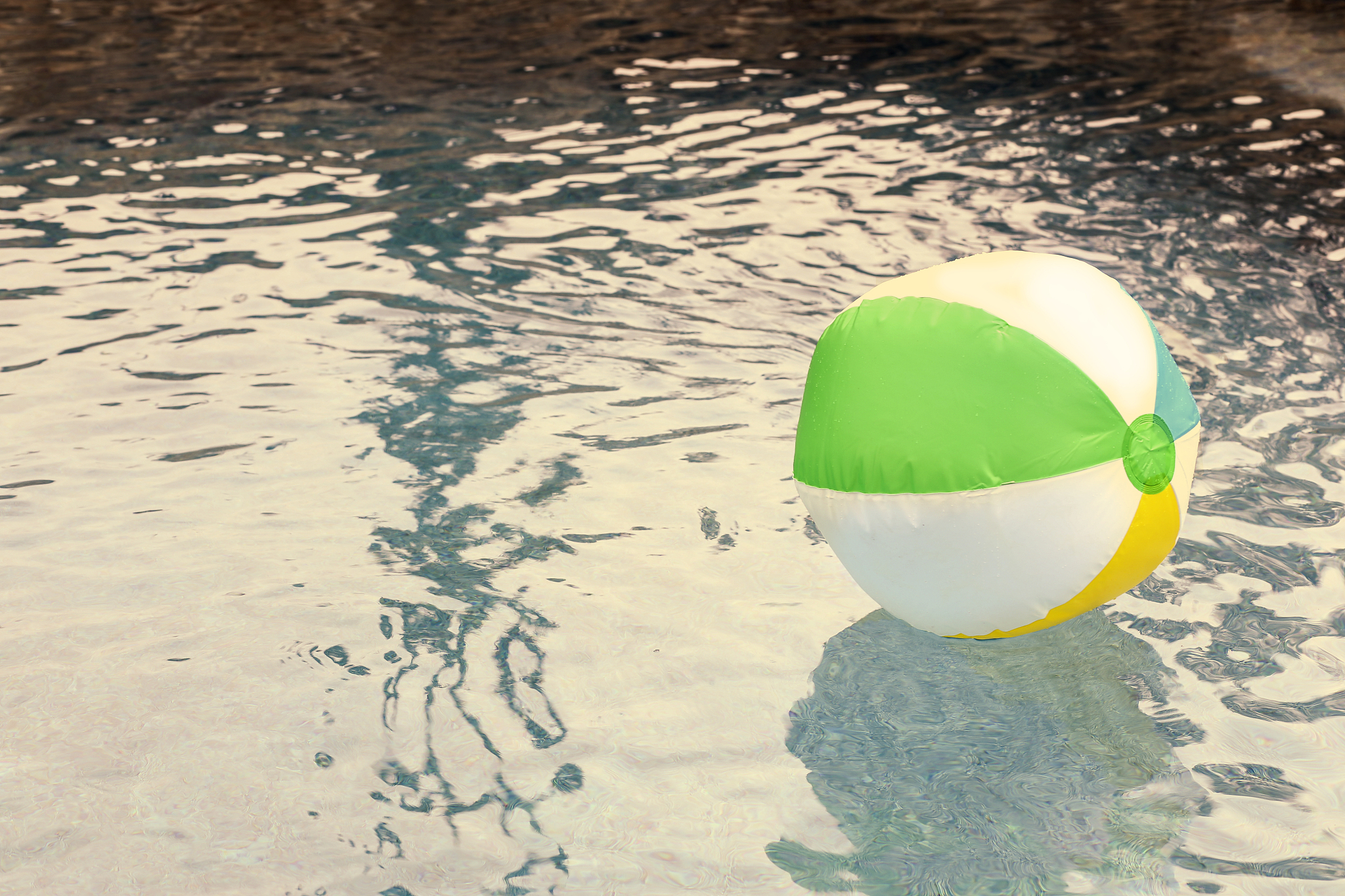 beach ball floating in refreshing swimming pool water.