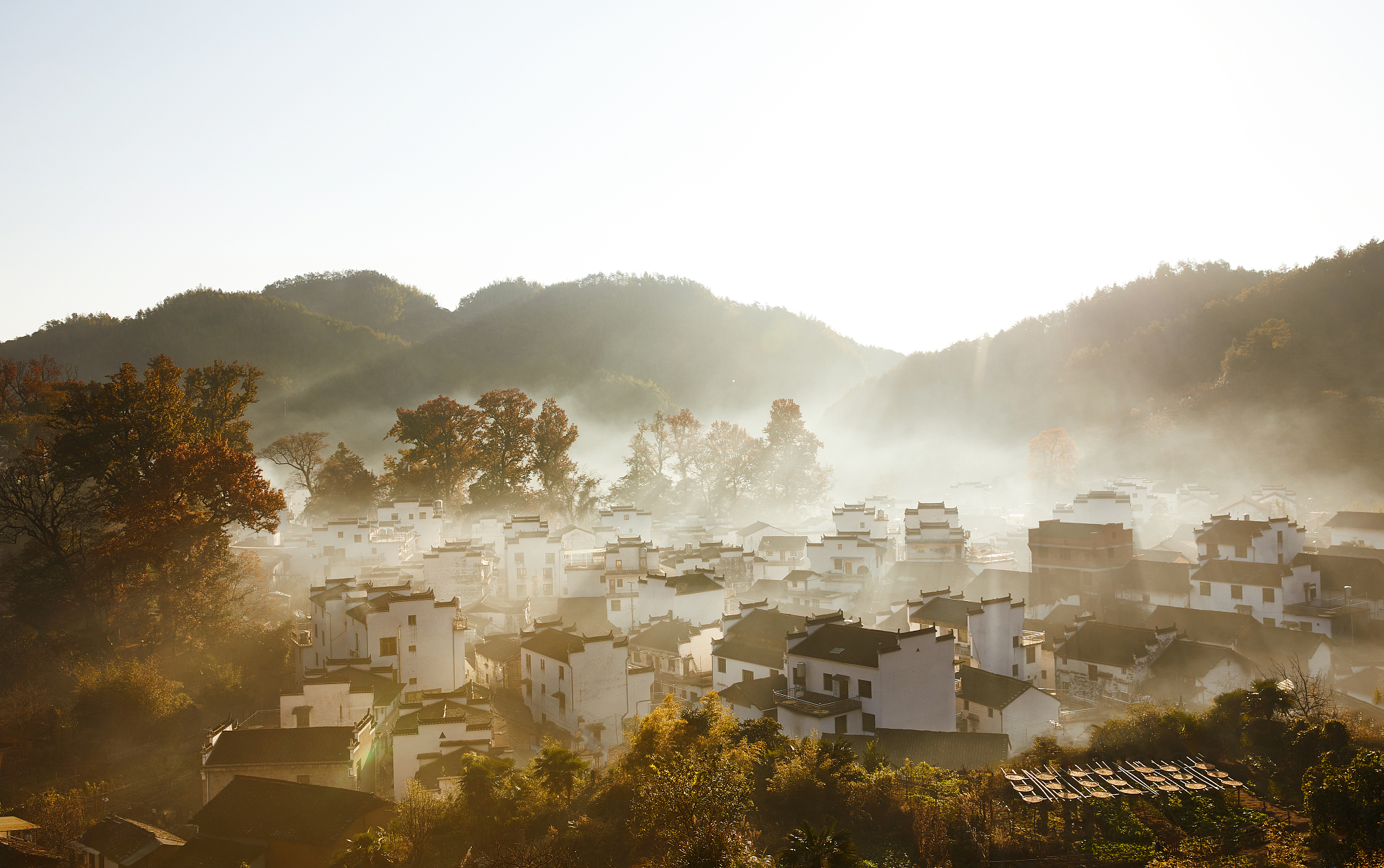 请用100字描述江西石城清晨薄雾笼罩村落若隐若现的场景
