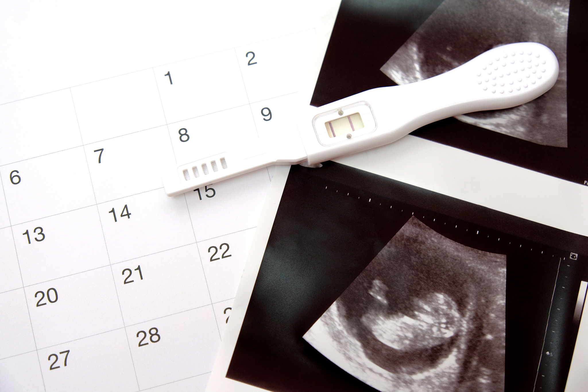 positive white plastic pregnancy test and  calendar with ultraso