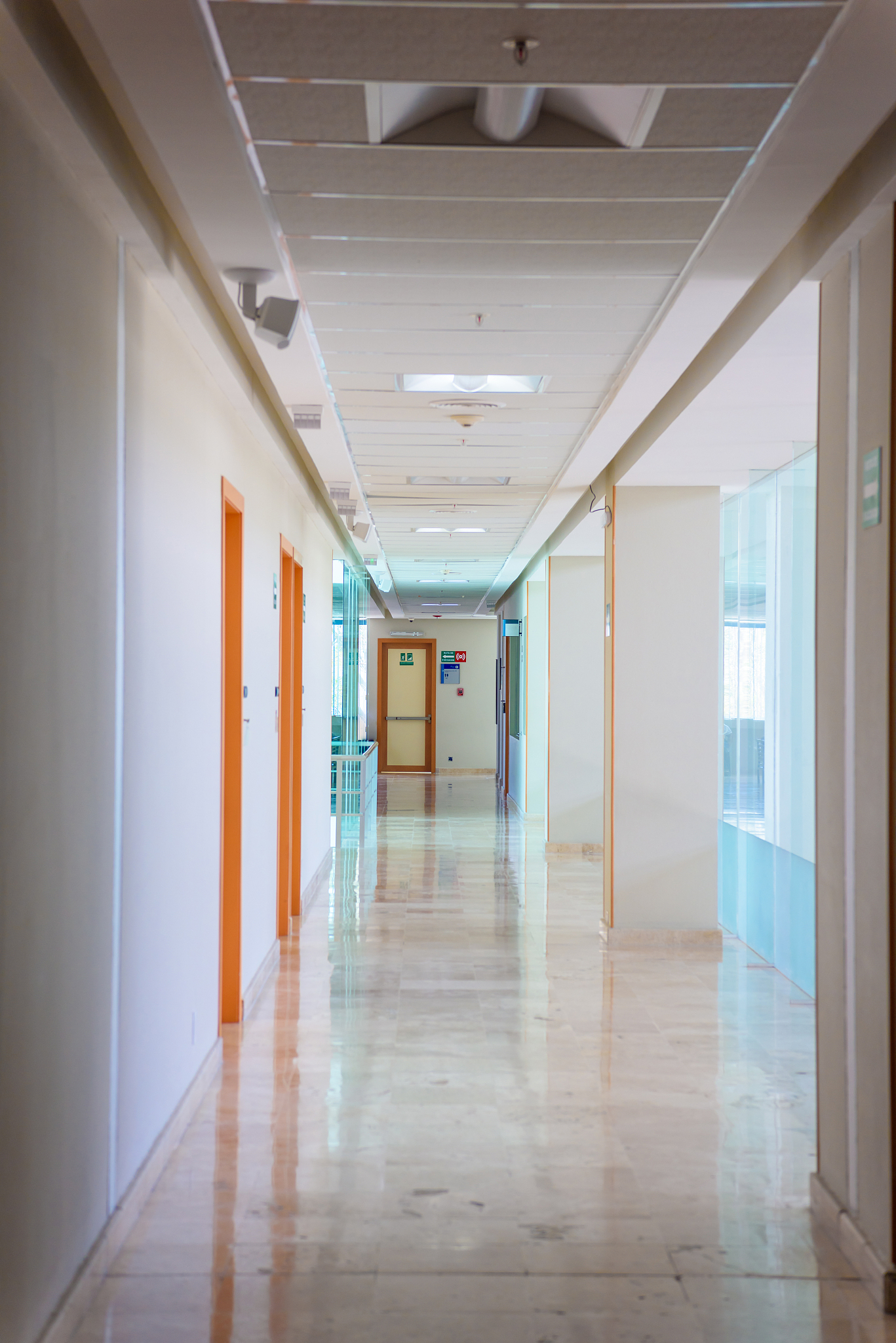 a huge brown door in a white corridor in a hospital.
