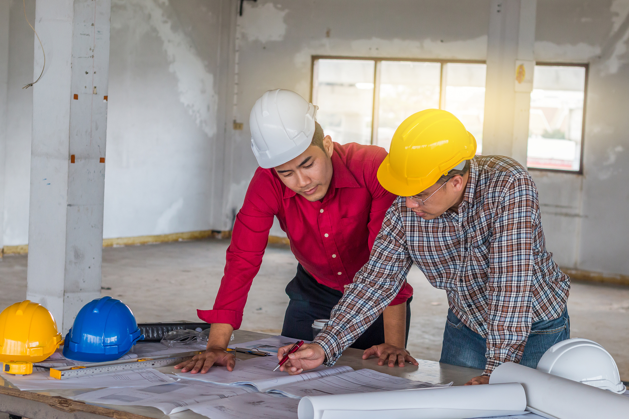 architectures discussing blueprint on desk at construction site