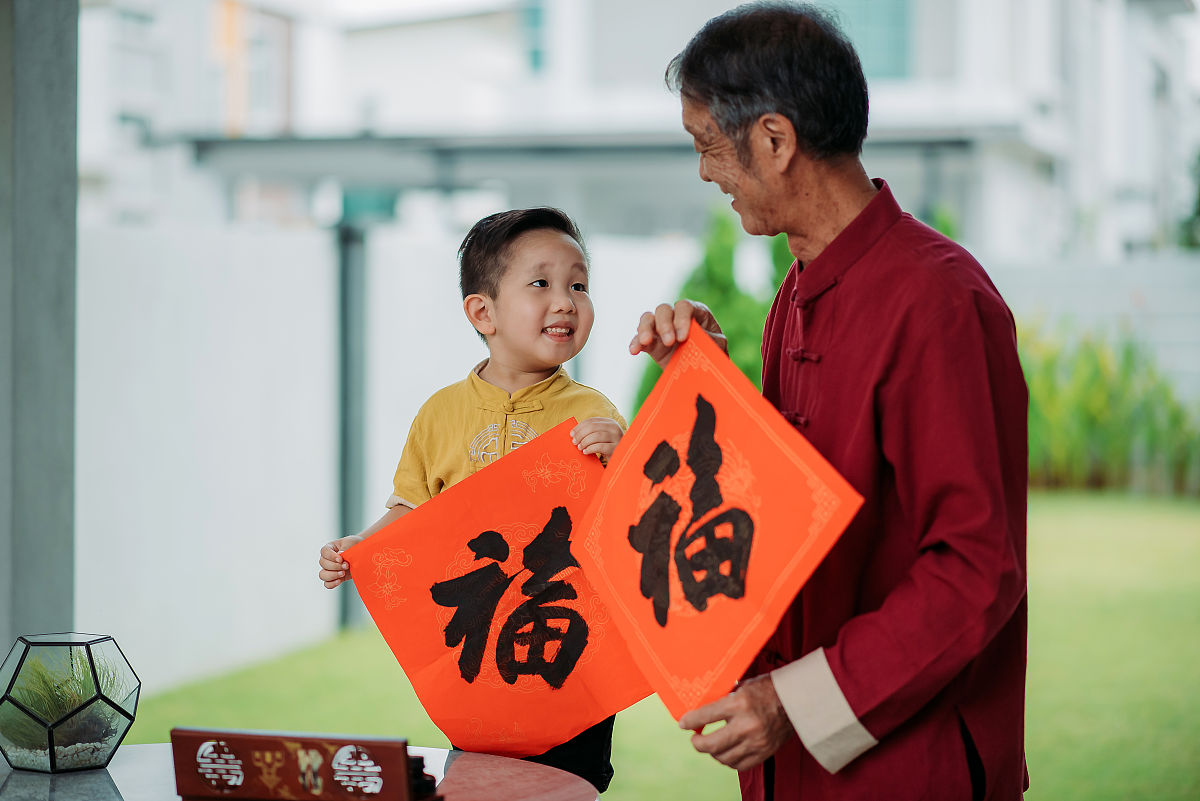亚洲华人微笑的爷爷和孙子手握中国书法在前院中国新年