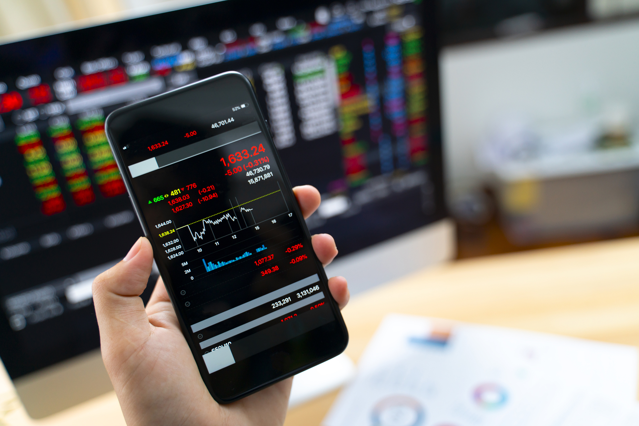hand holding smart phone displaying stock market data,