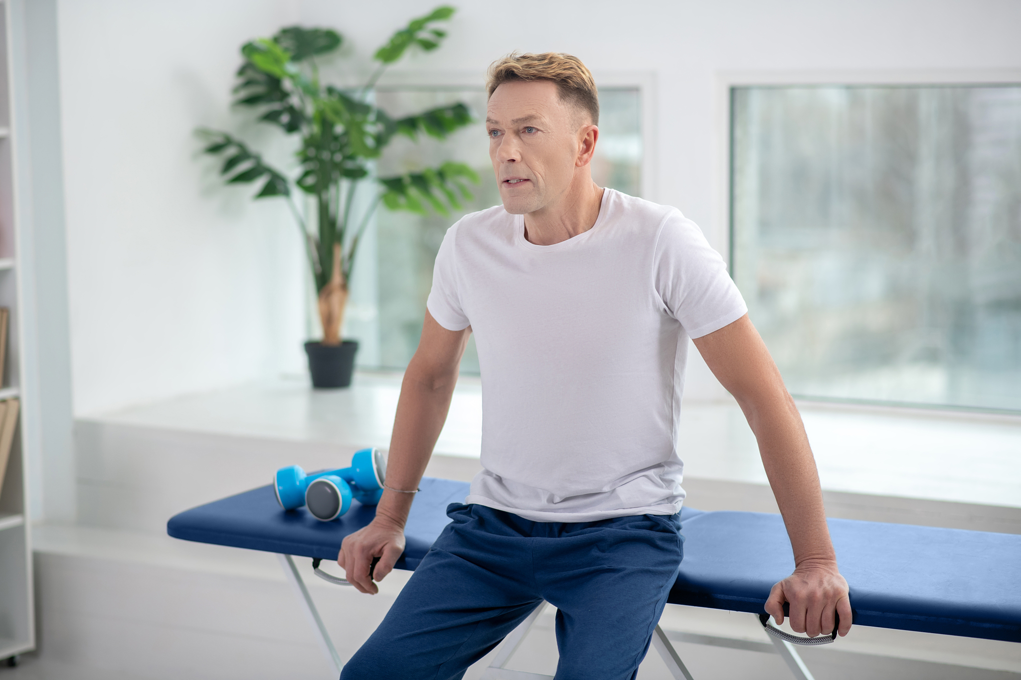 male physiotherapist sitting on couch, waiting for patient