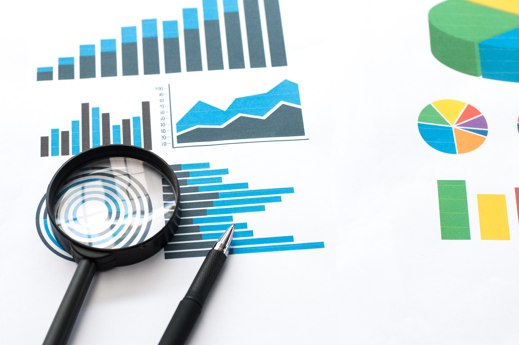 papers with business report and magnifying glass