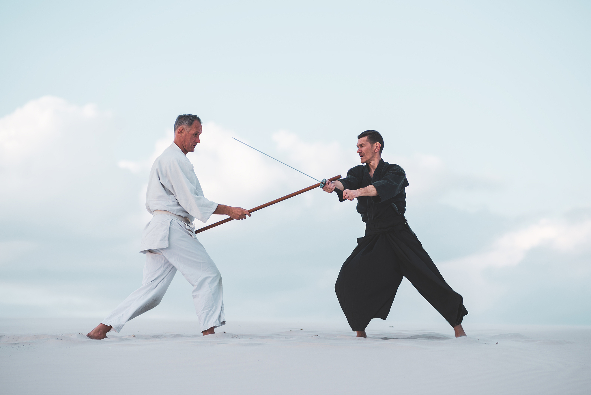 two men practicing japanese martial arts in desert