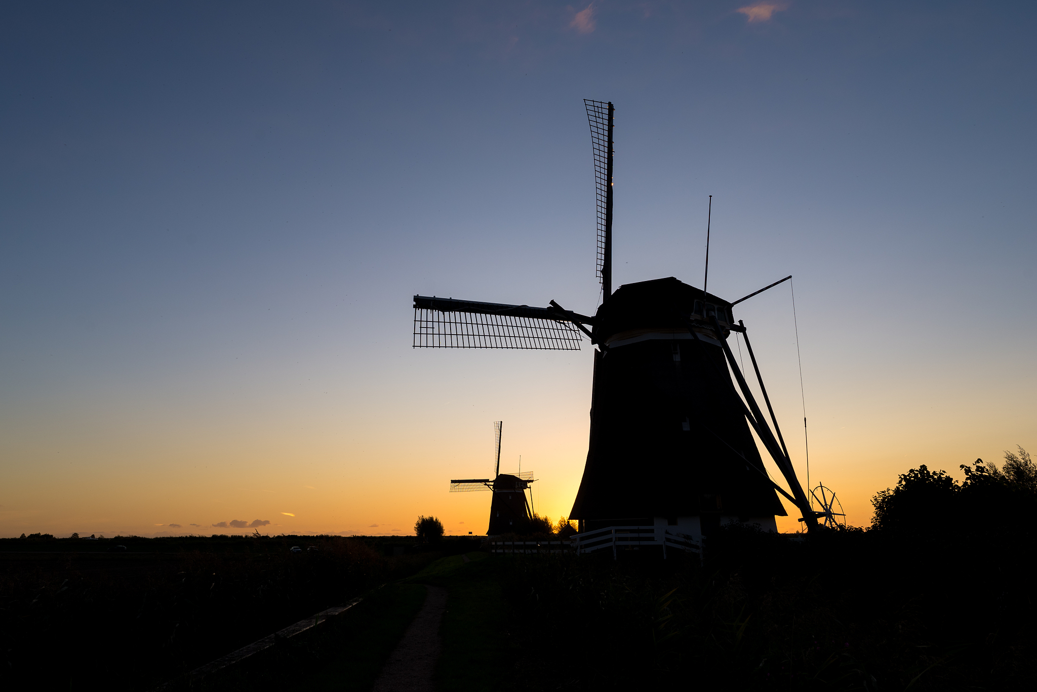 windmills are silhouetted against the evening sky