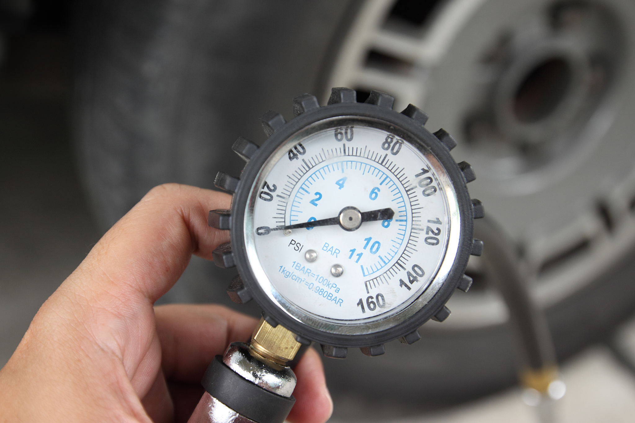 hand holding pressure gauge for car tyre pressure measurement