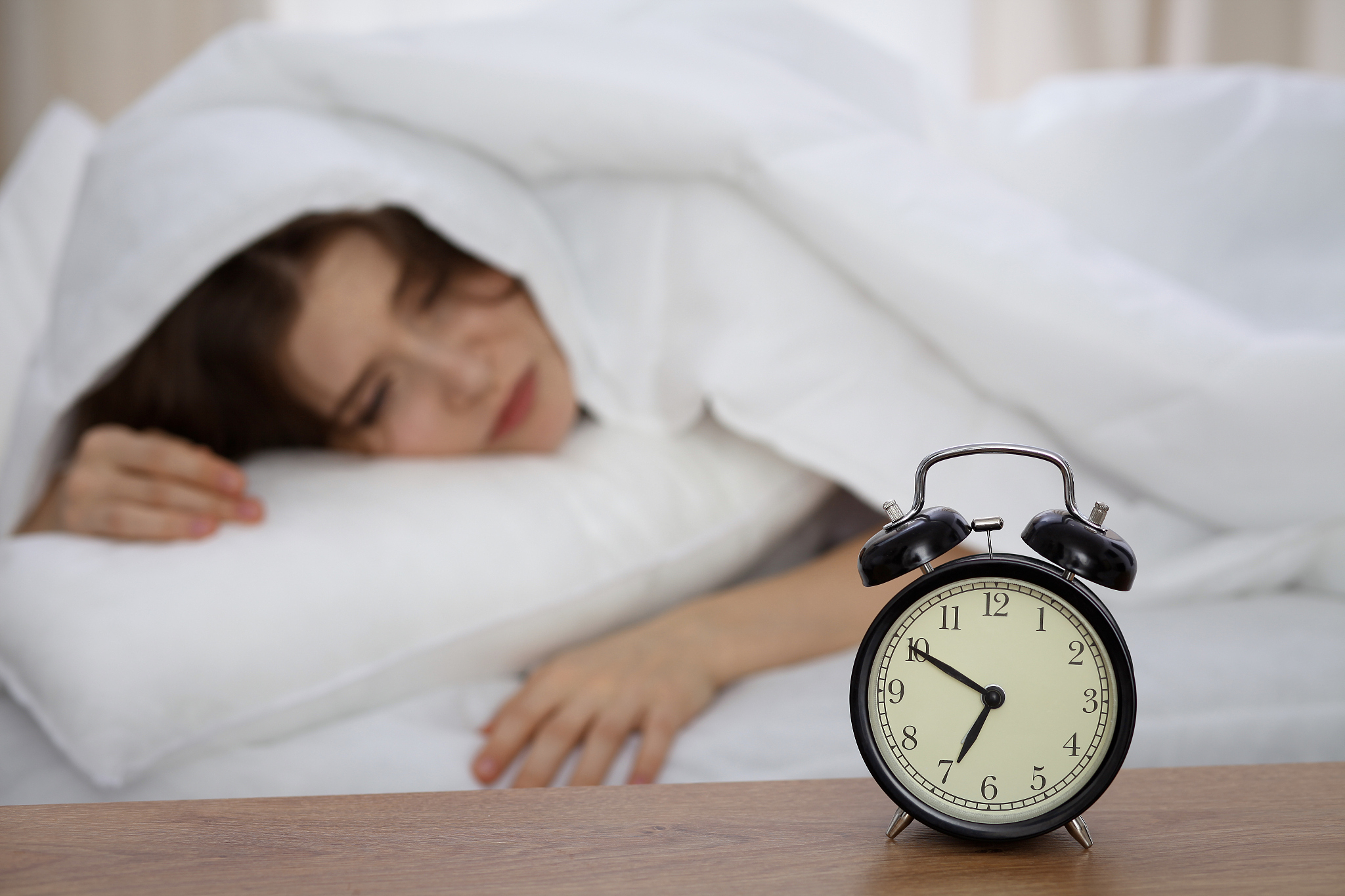 beautiful sleeping woman lying in bed and trying to wake up with