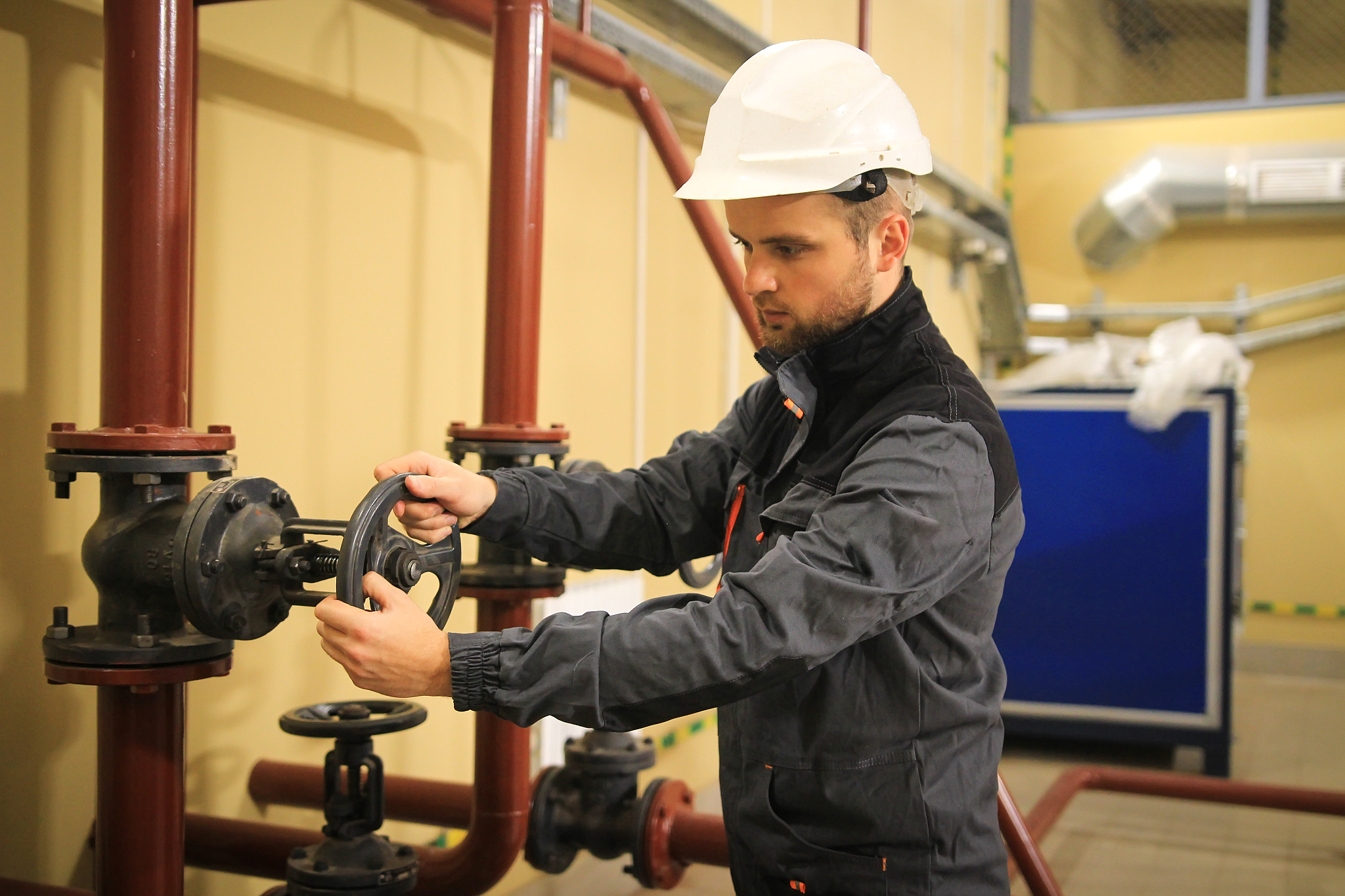 engineer closes gate valve on industrial pipeline