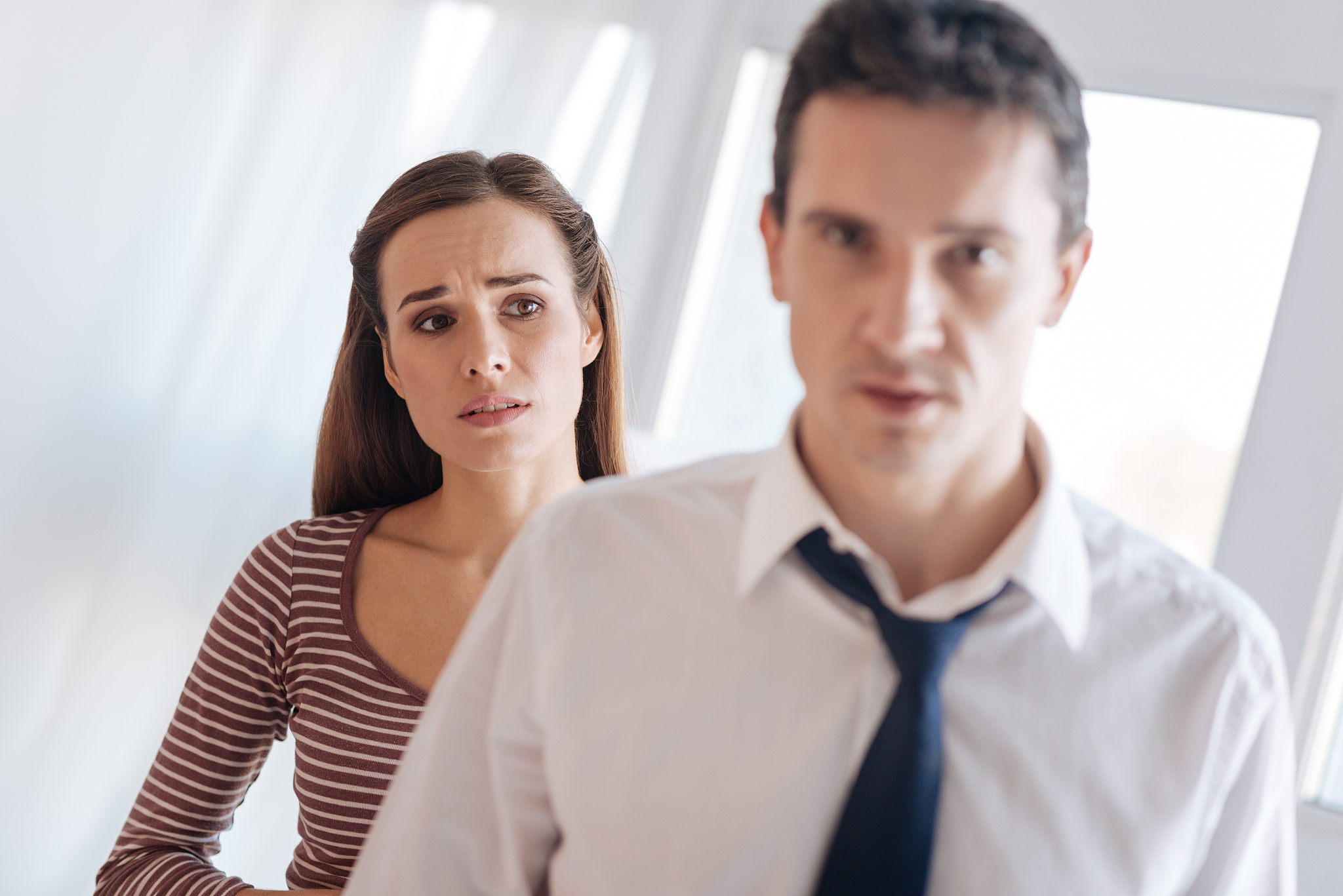 worried kind woman looking at her irritated tired husband