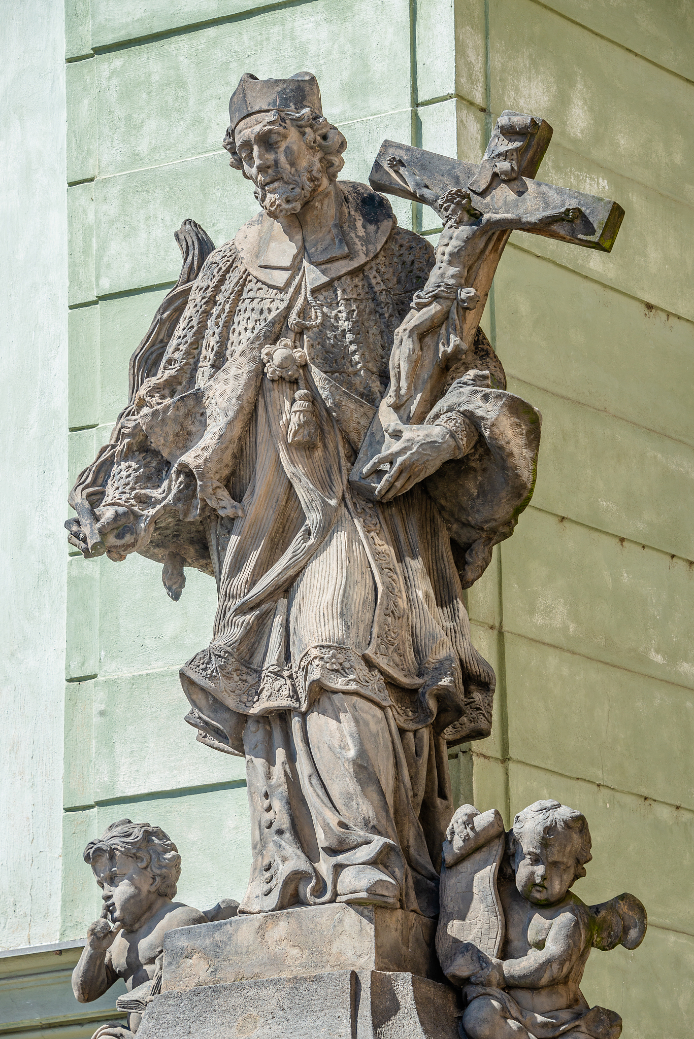 statue of old priest with cross and jesus at old town in prague,