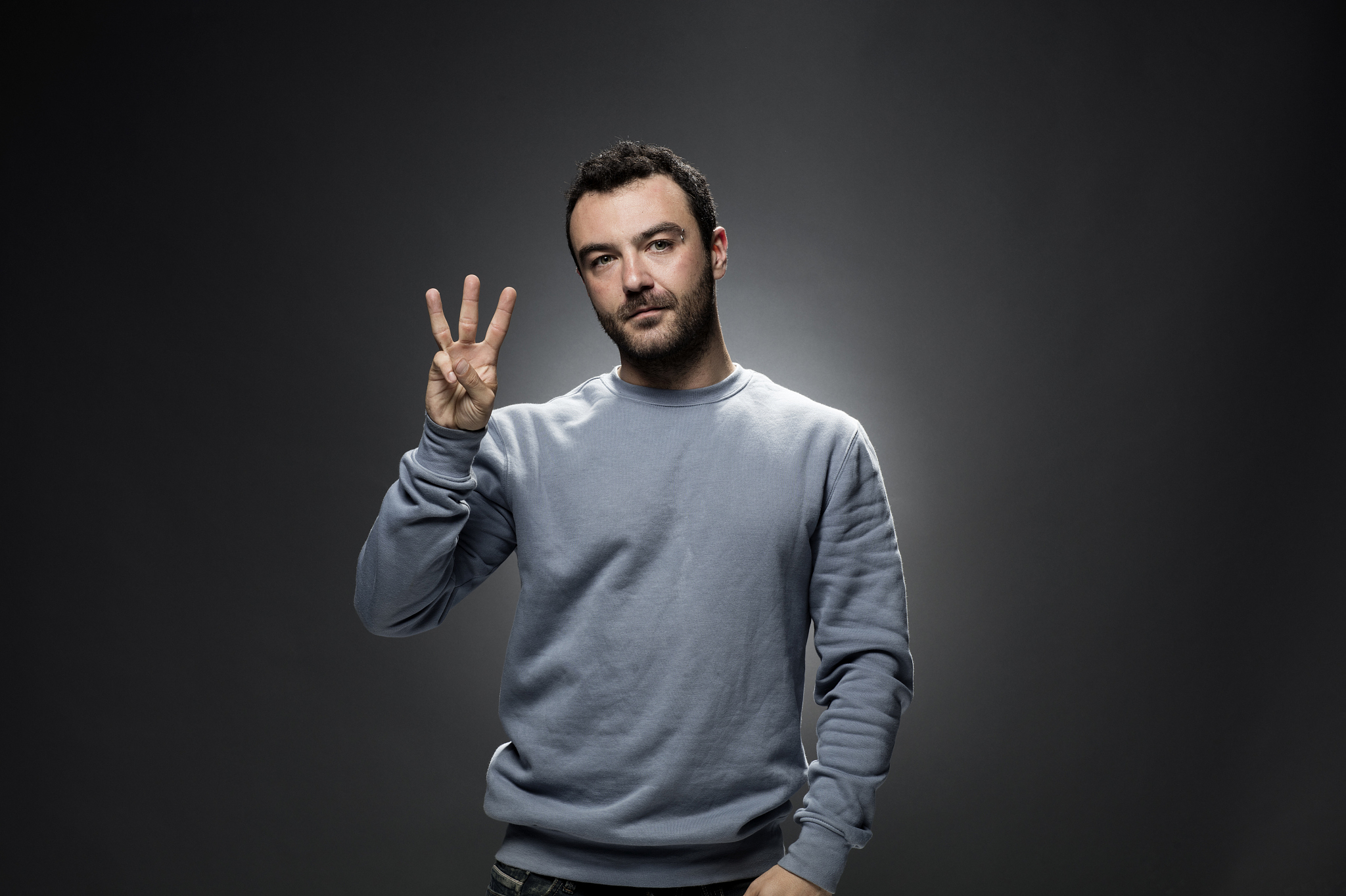 young man showing number three with fingers