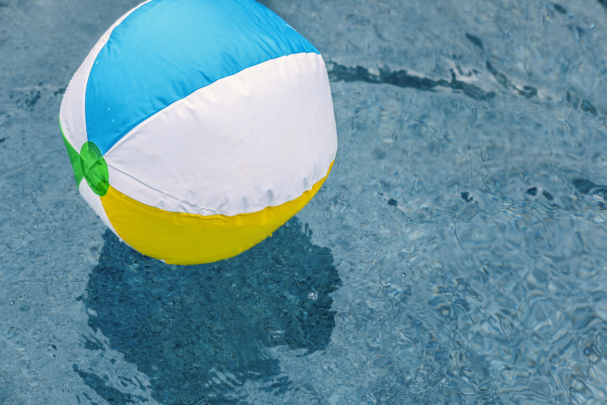 beach ball floating in refreshing swimming pool water.