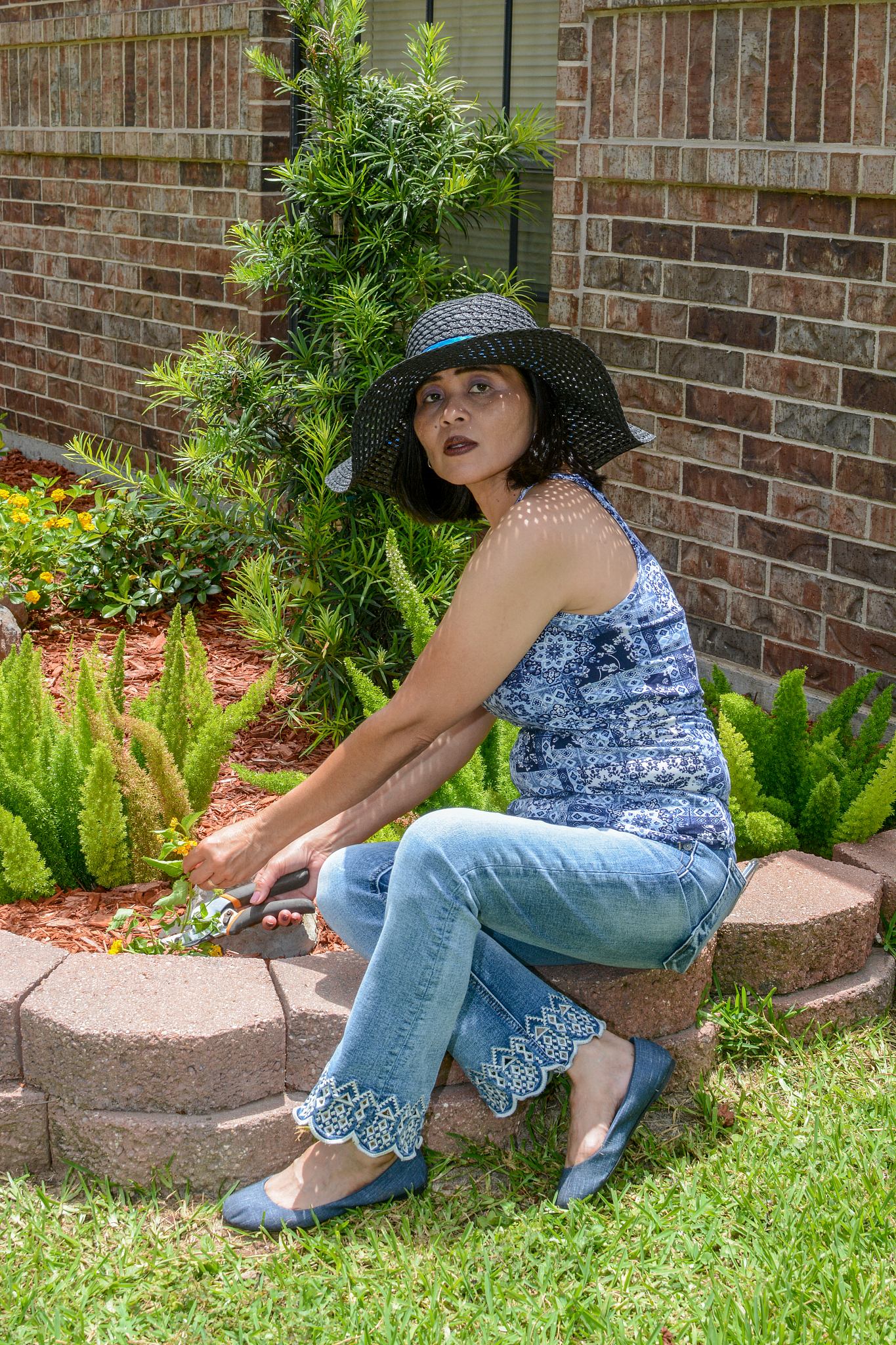 outdoor scene with filipino woman sitting by flower garden