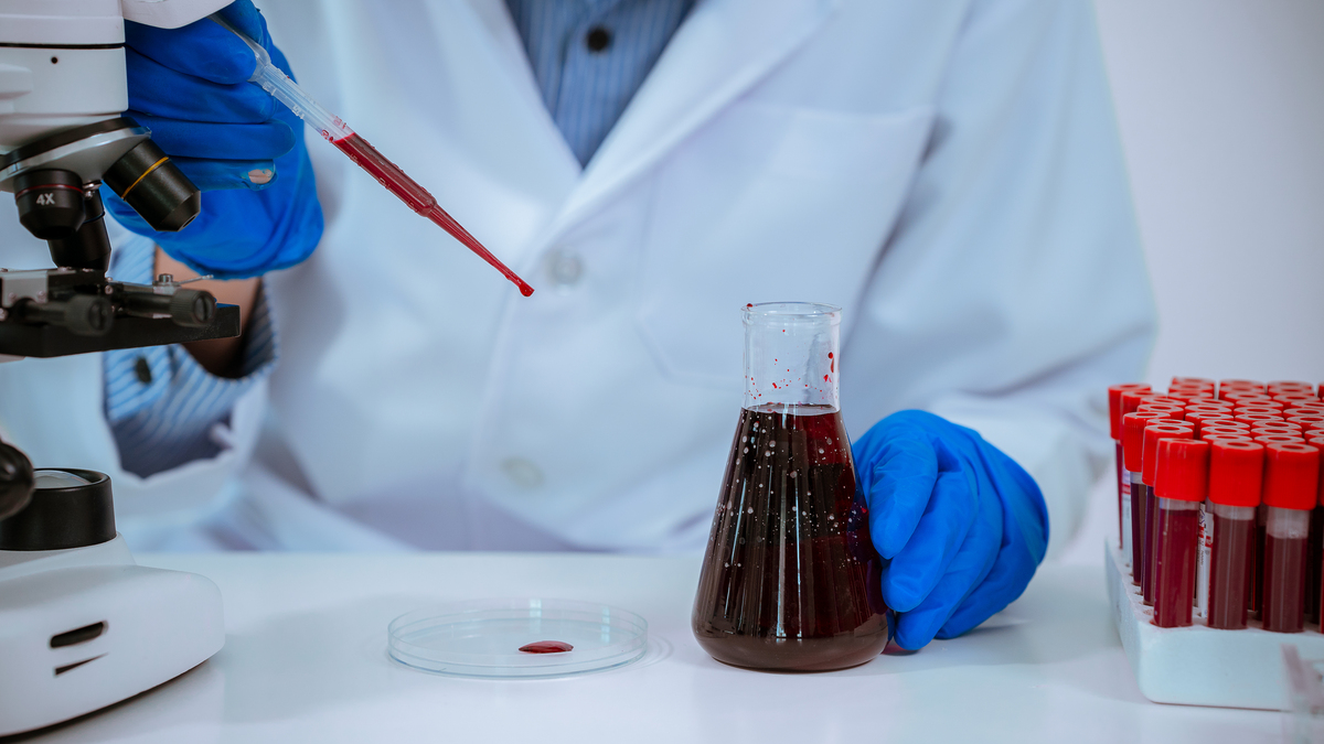 科学.医生从架子上拿起一支用于实验室分析的血样管,.